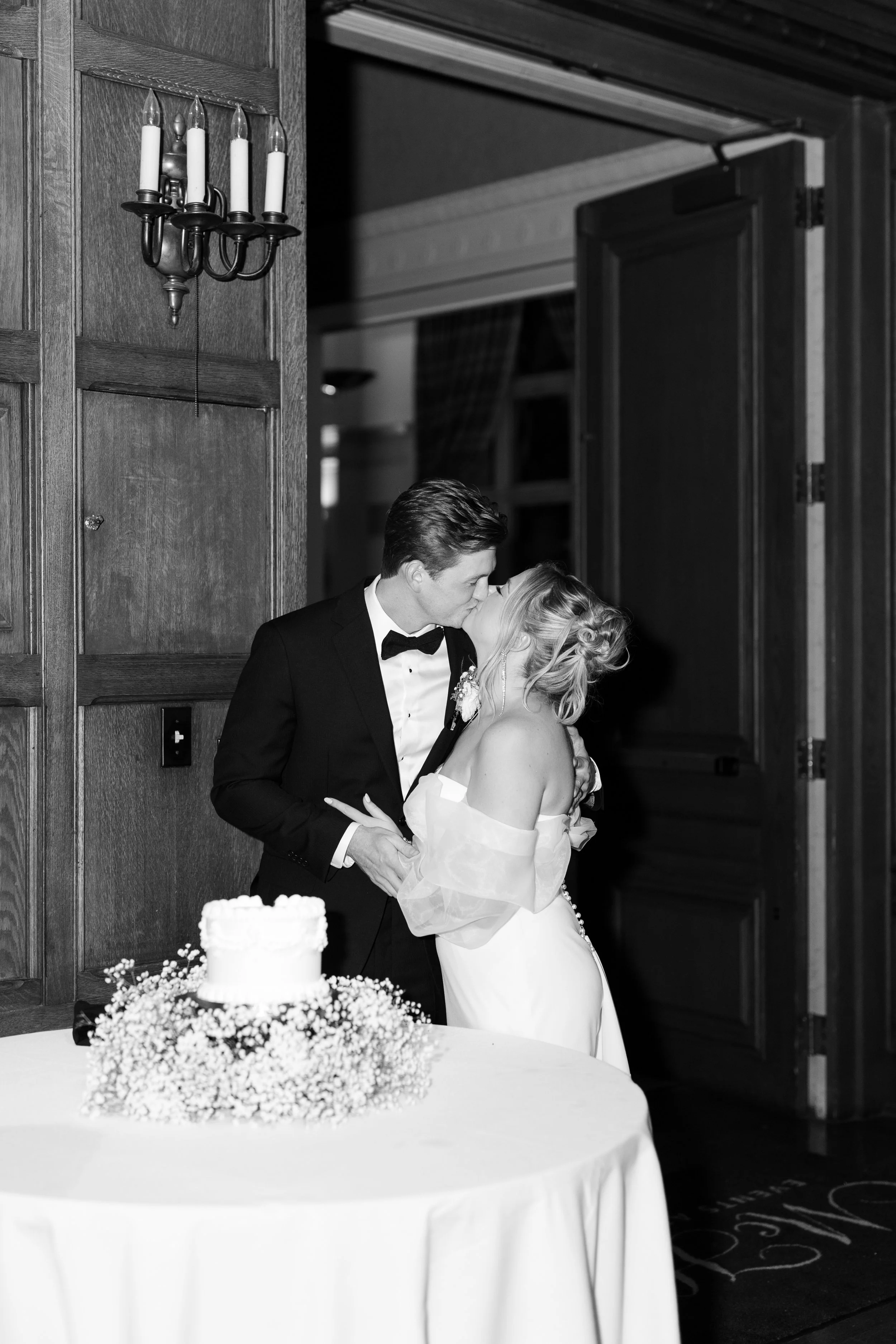 Newlyweds smile while cutting their wedding cake during the reception celebration.