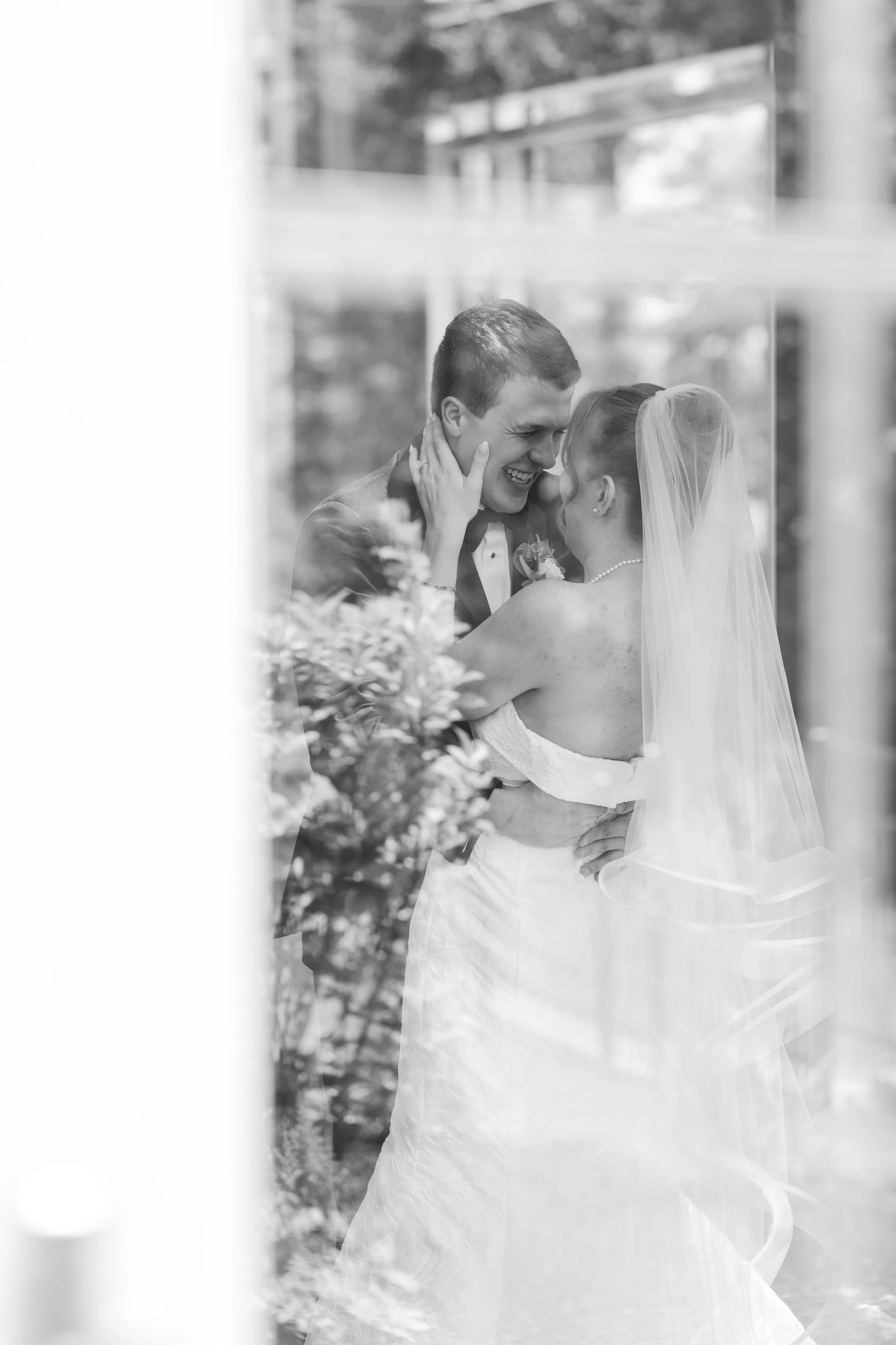 Romantic black-and-white portrait of the bride and groom embracing during their wedding day.