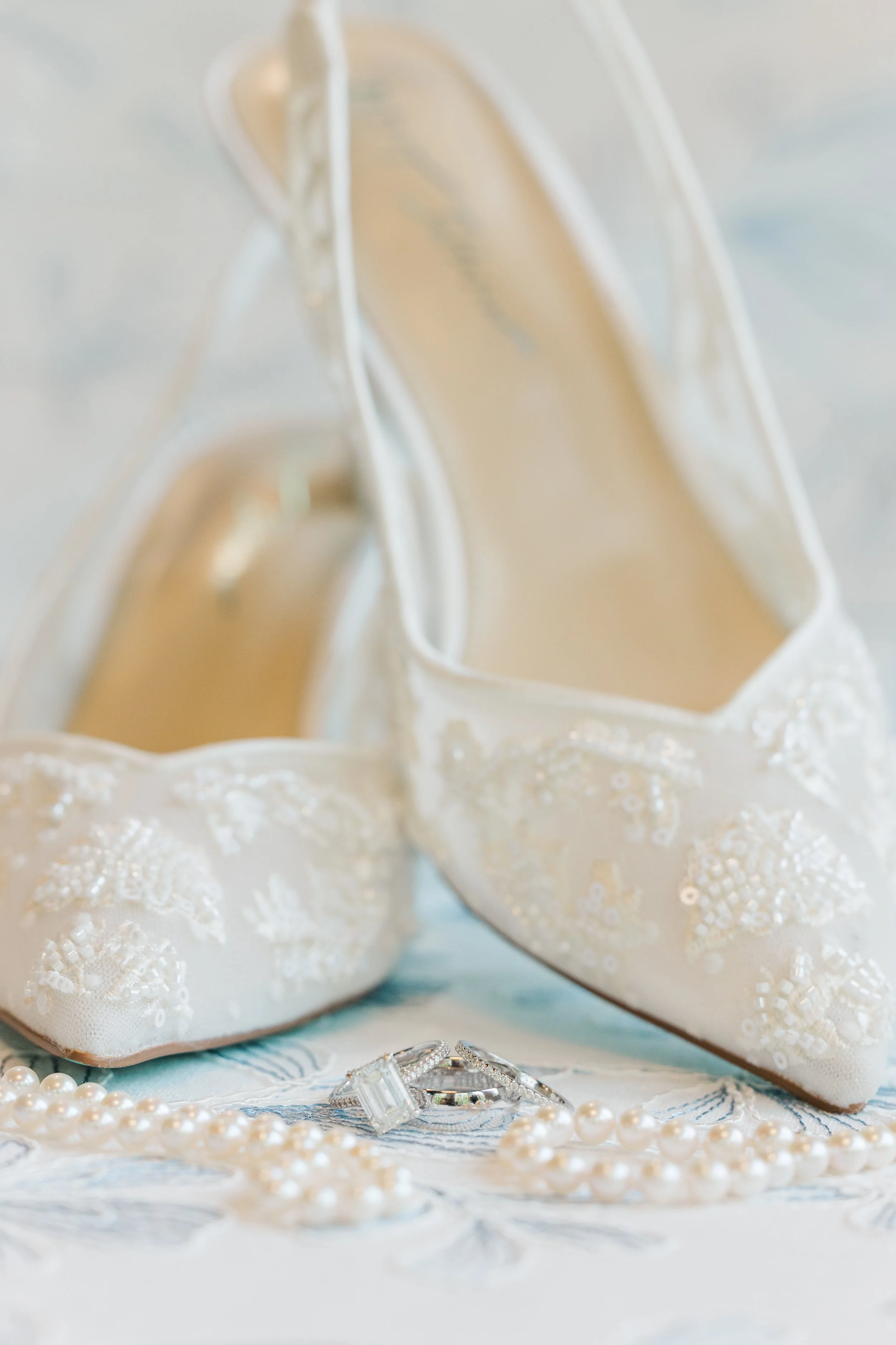 Sparkling bridal shoes displayed beneath a delicate wedding veil before the ceremony.