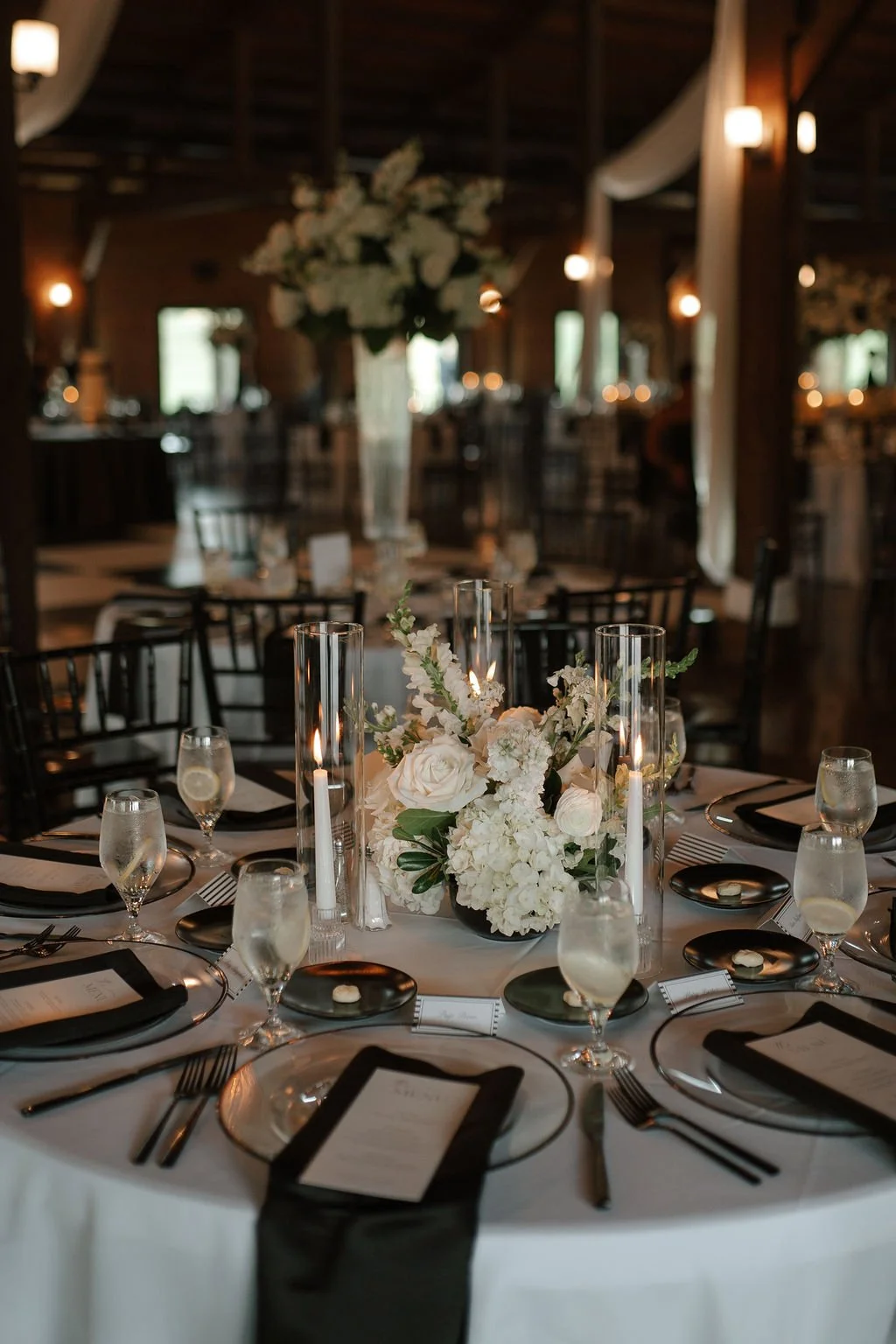 Black and white wedding reception table with white floral centerpiece and candlelight