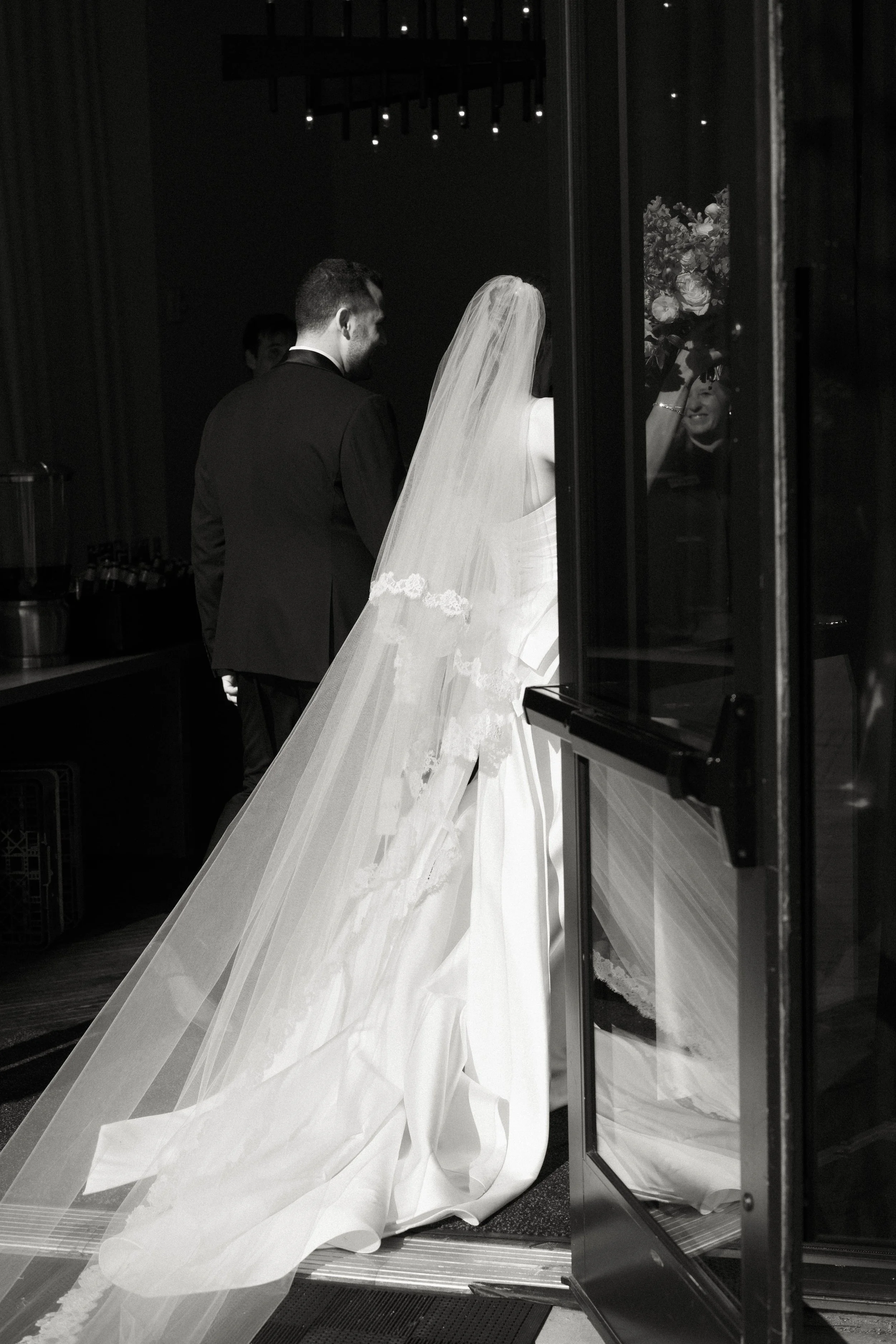 Bride enters the ceremony with her veil flowing behind her as she walks into the church.