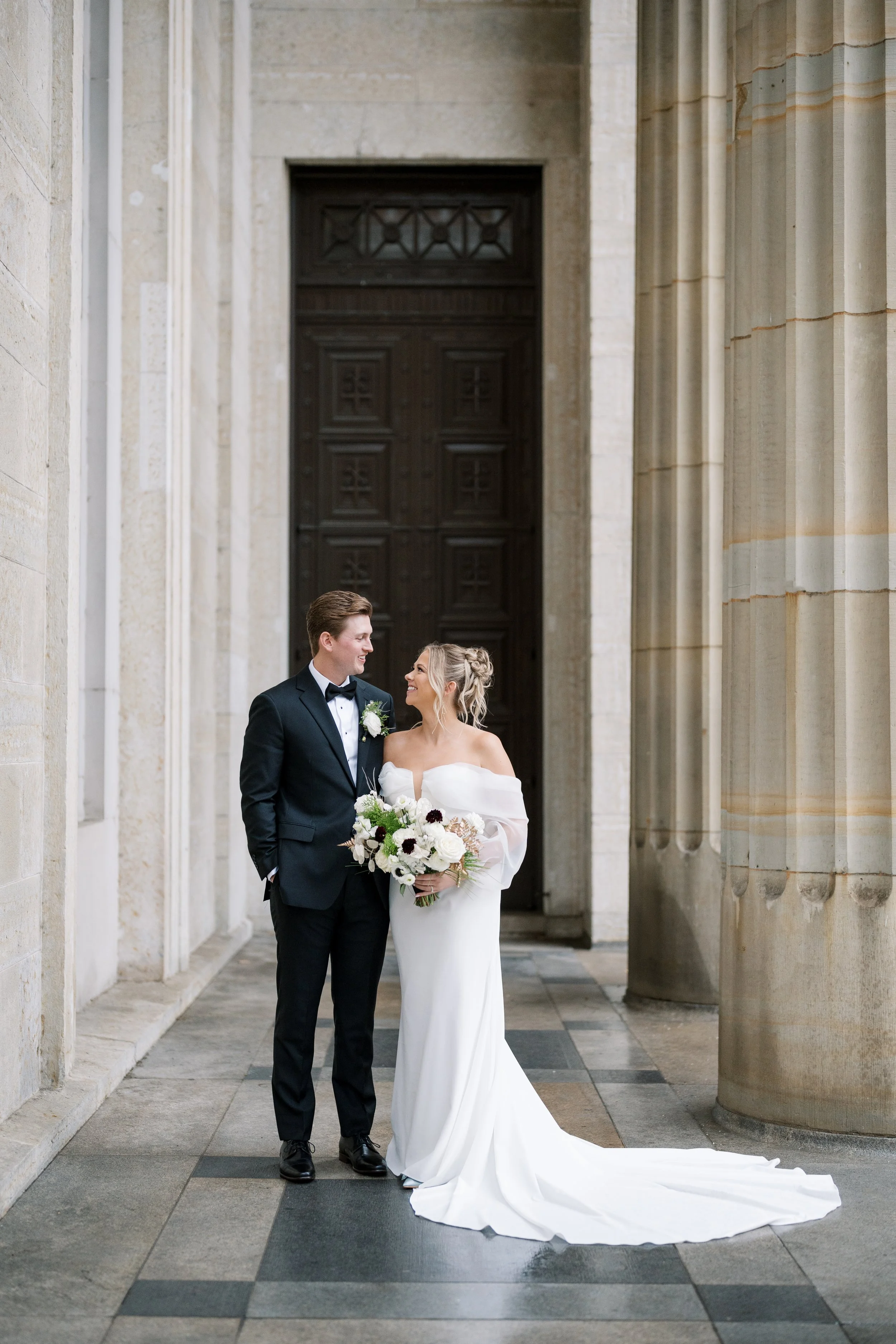 Bride and groom sharing a quiet moment beneath the grand columns of the Cincinnati Art Museum on their wedding day.