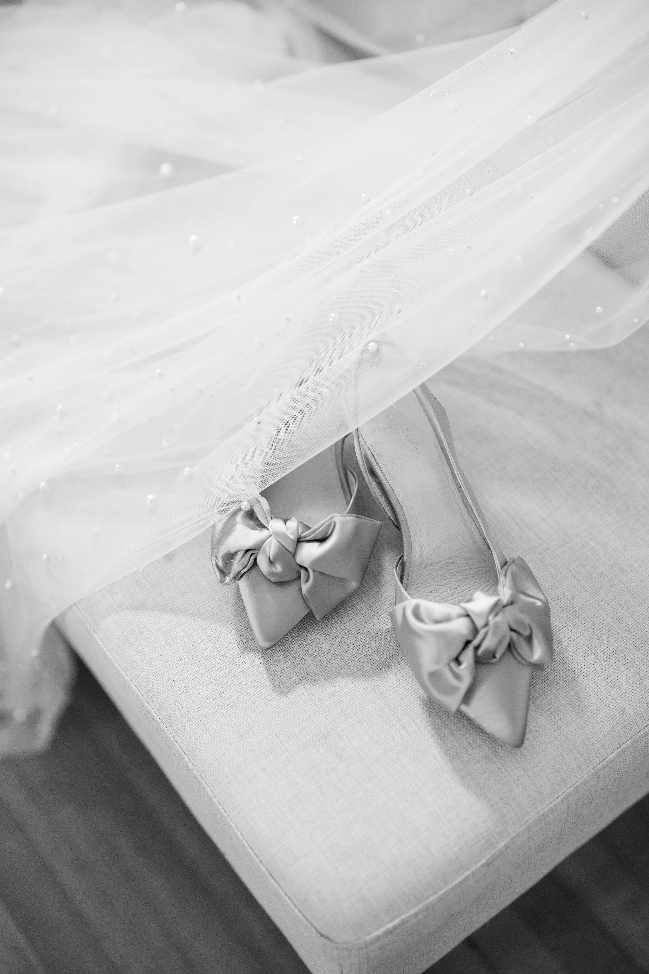 Sparkling bridal shoes displayed beneath a delicate wedding veil before the ceremony.