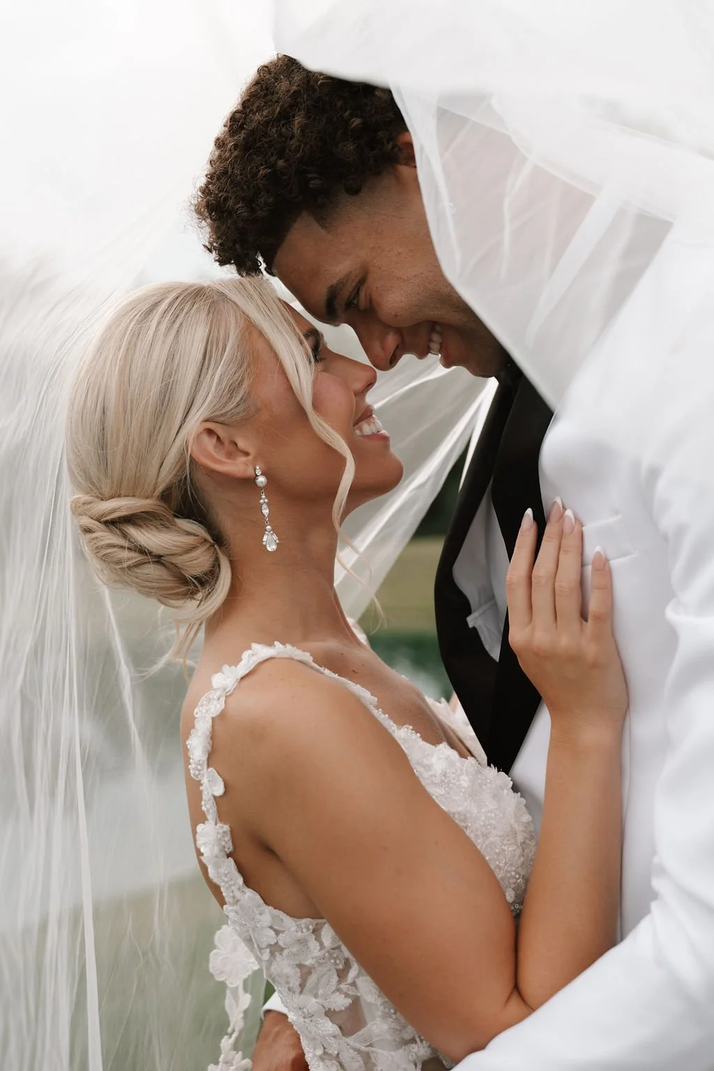Romantic wedding portrait of a bride and groom beneath the bridal veil, showcasing timeless wedding photography and authentic emotion.