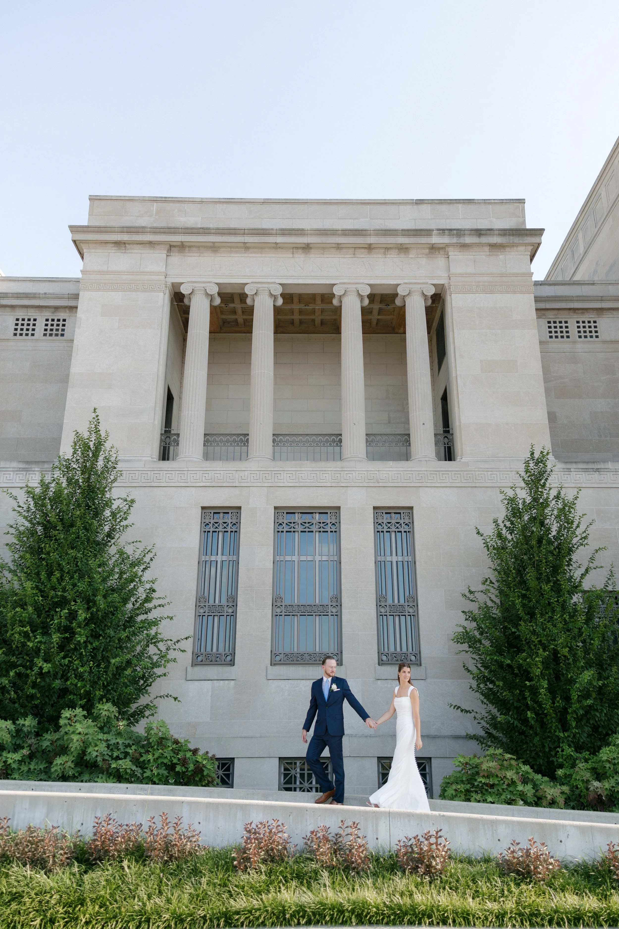 Bride and groom holding hands outside the Cincinnati Art Museum during their wedding portraits.
