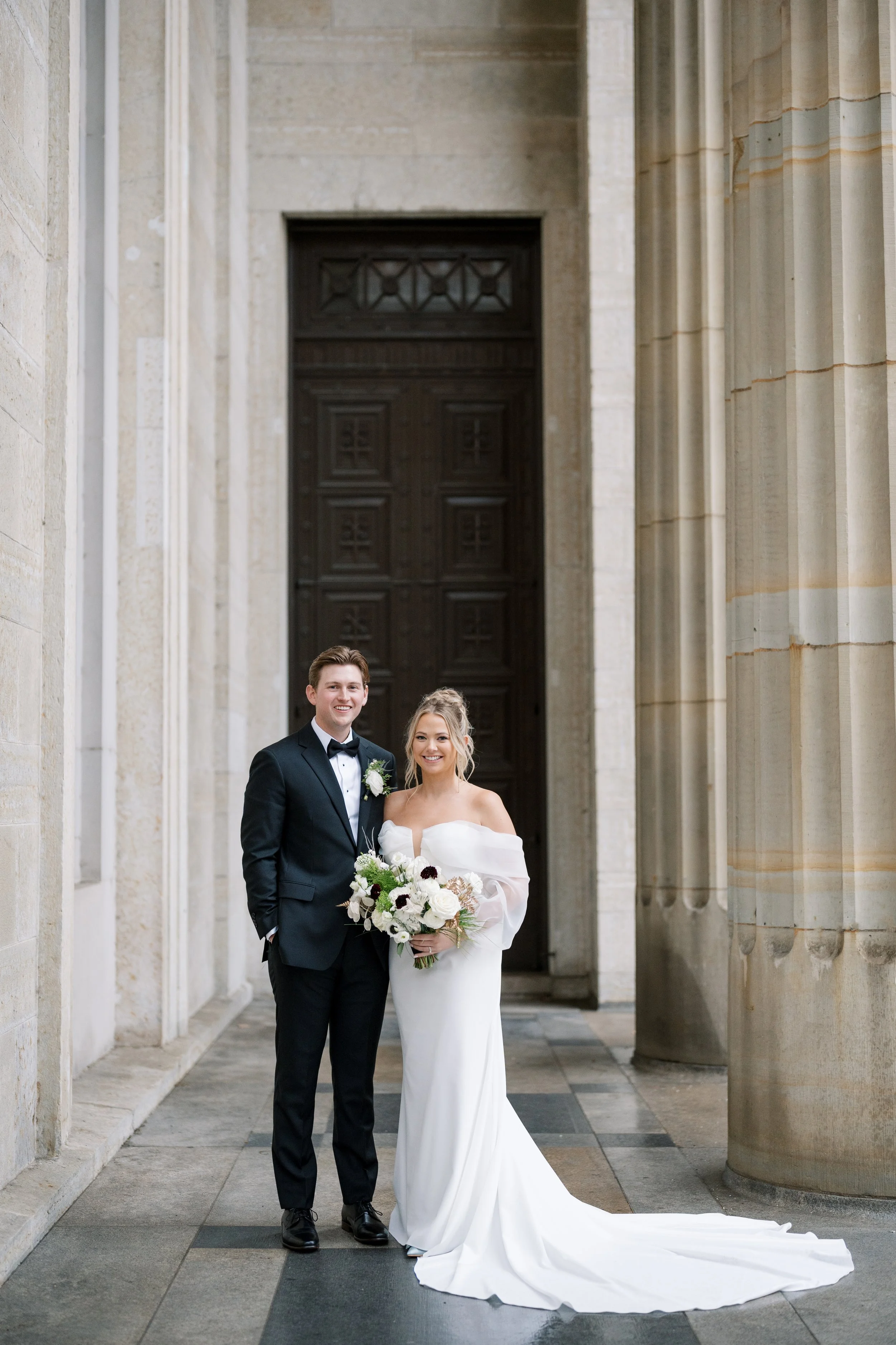 Bride and groom sharing a quiet moment beneath the historic columns of the Cincinnati Art Museum.