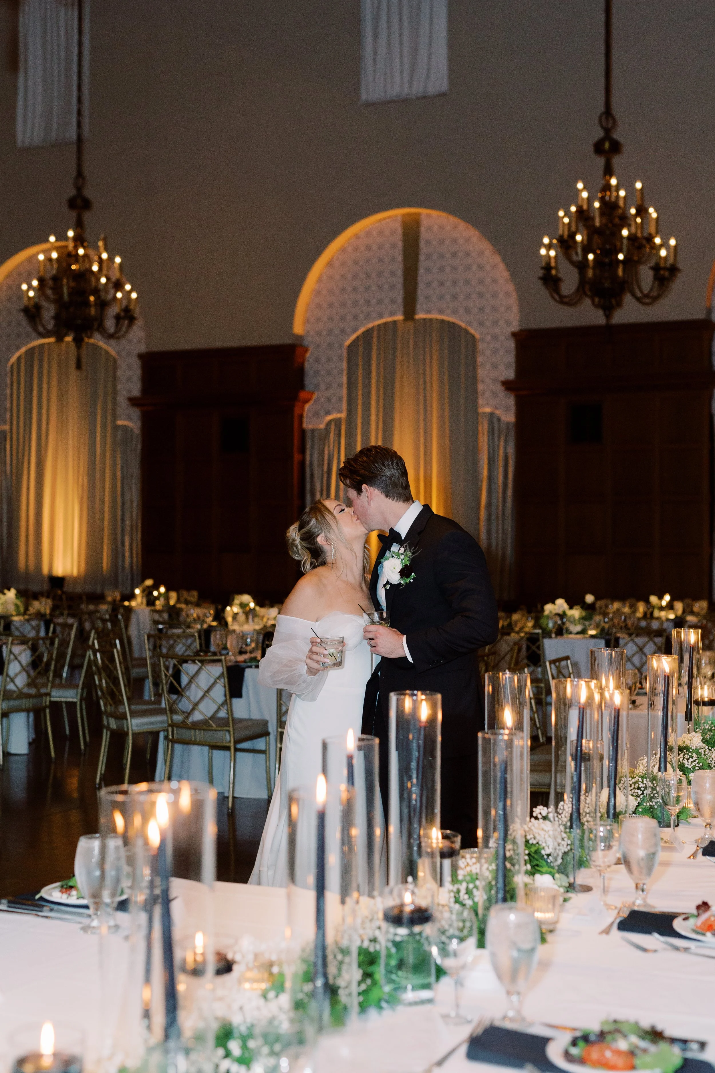 Bride and groom embracing during their candlelit wedding reception surrounded by elegant floral arrangements and glowing candles at The Cincinnati Club.