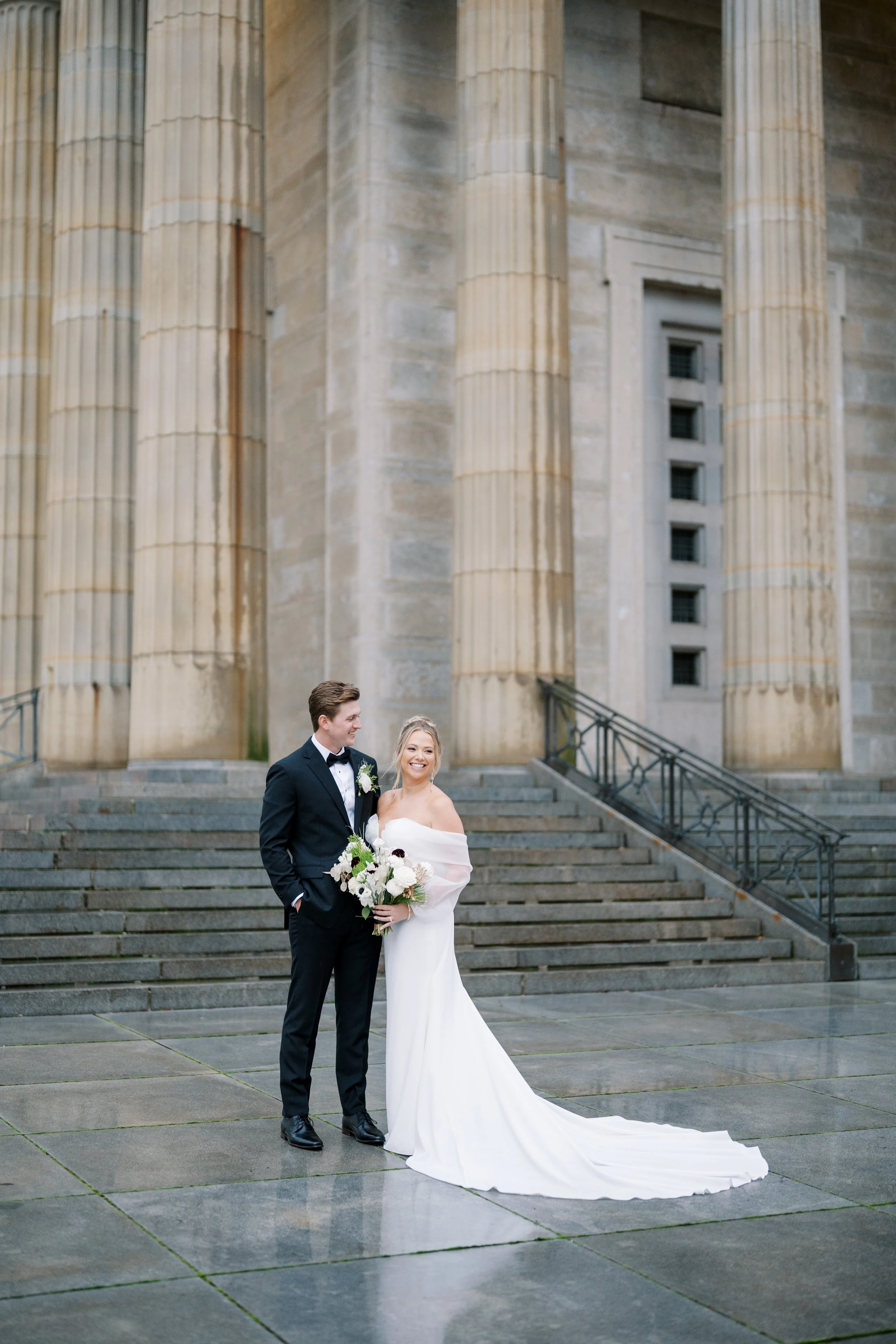 Bride and groom share a portrait outside a historic stone building, showcasing timeless wedding architecture and elegant bridal style.
