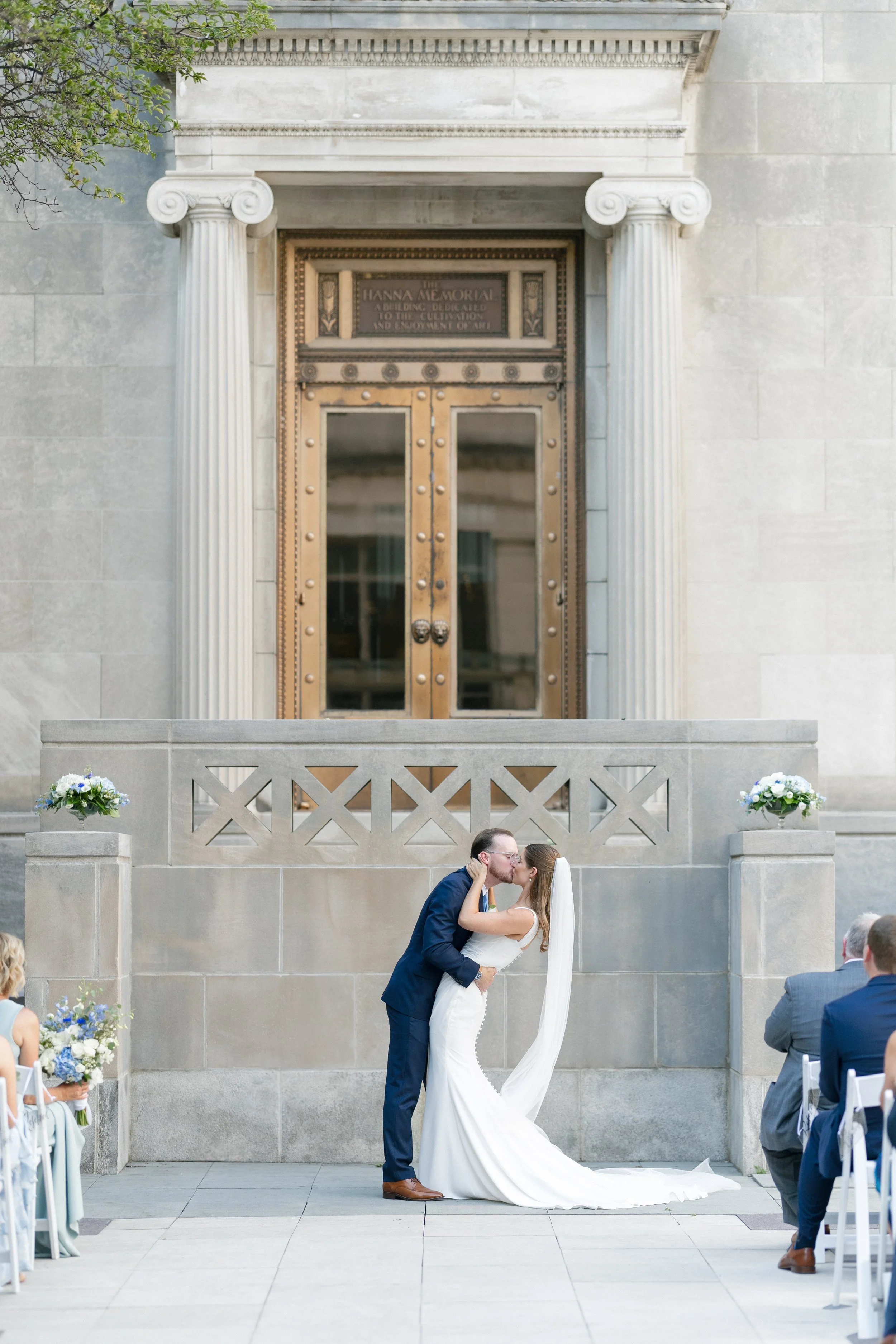 Bride and groom sharing their first kiss beneath the grand entrance of the Cincinnati Art Museum.