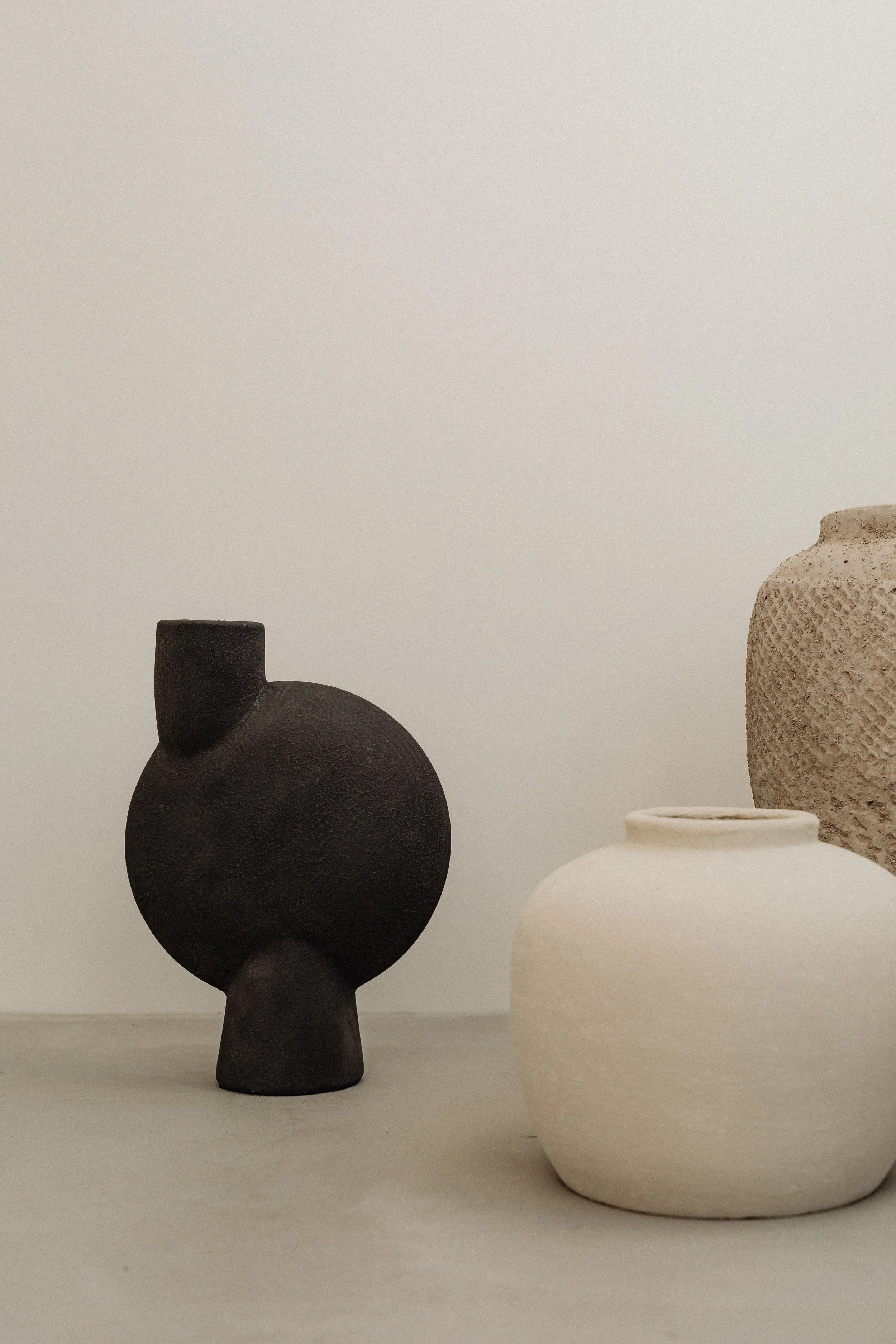 Black and white ceramic vases with textured surface, placed on a plain surface against a neutral background.