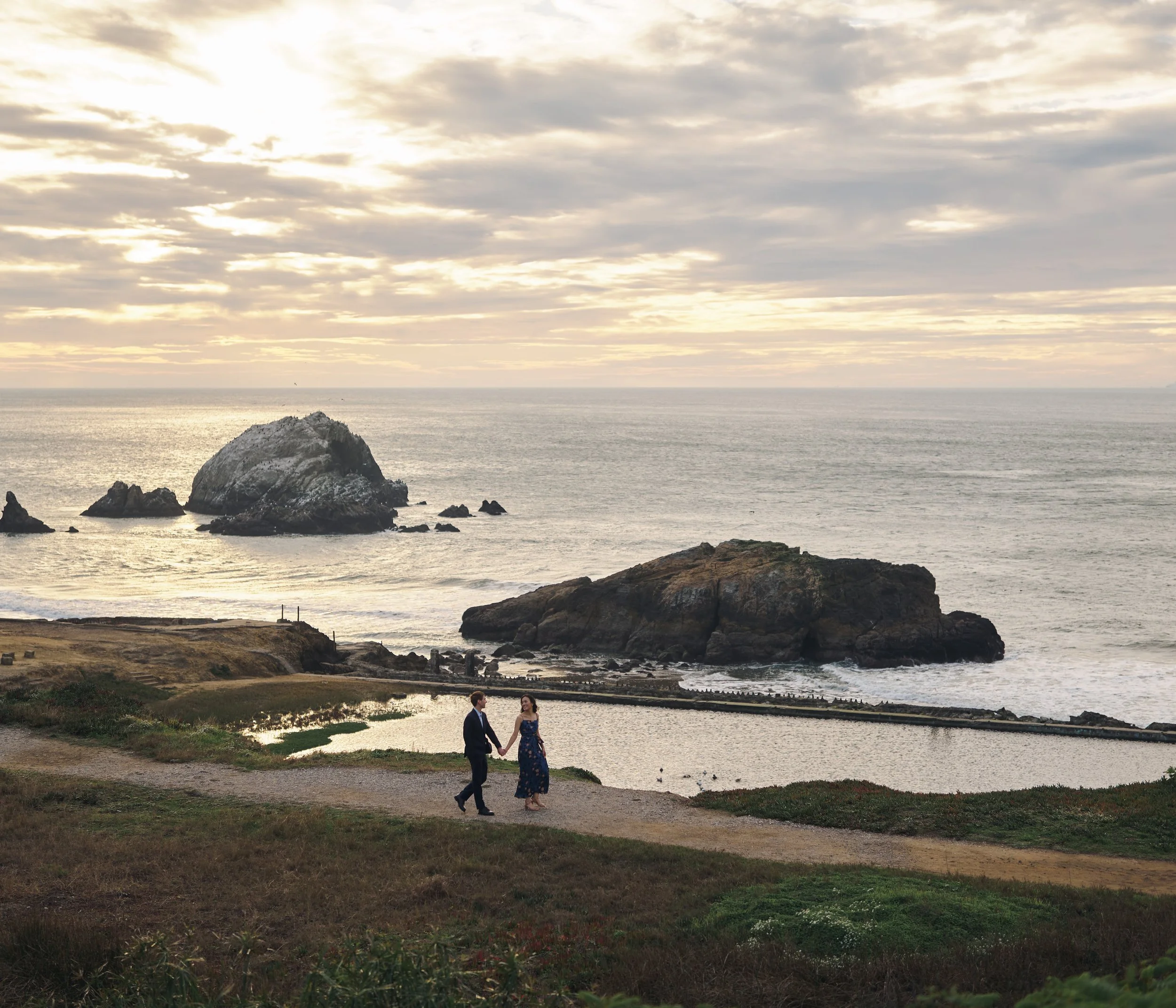Walking the Sutro Baths reflecting pool path at golden hour, San Francisco engagement