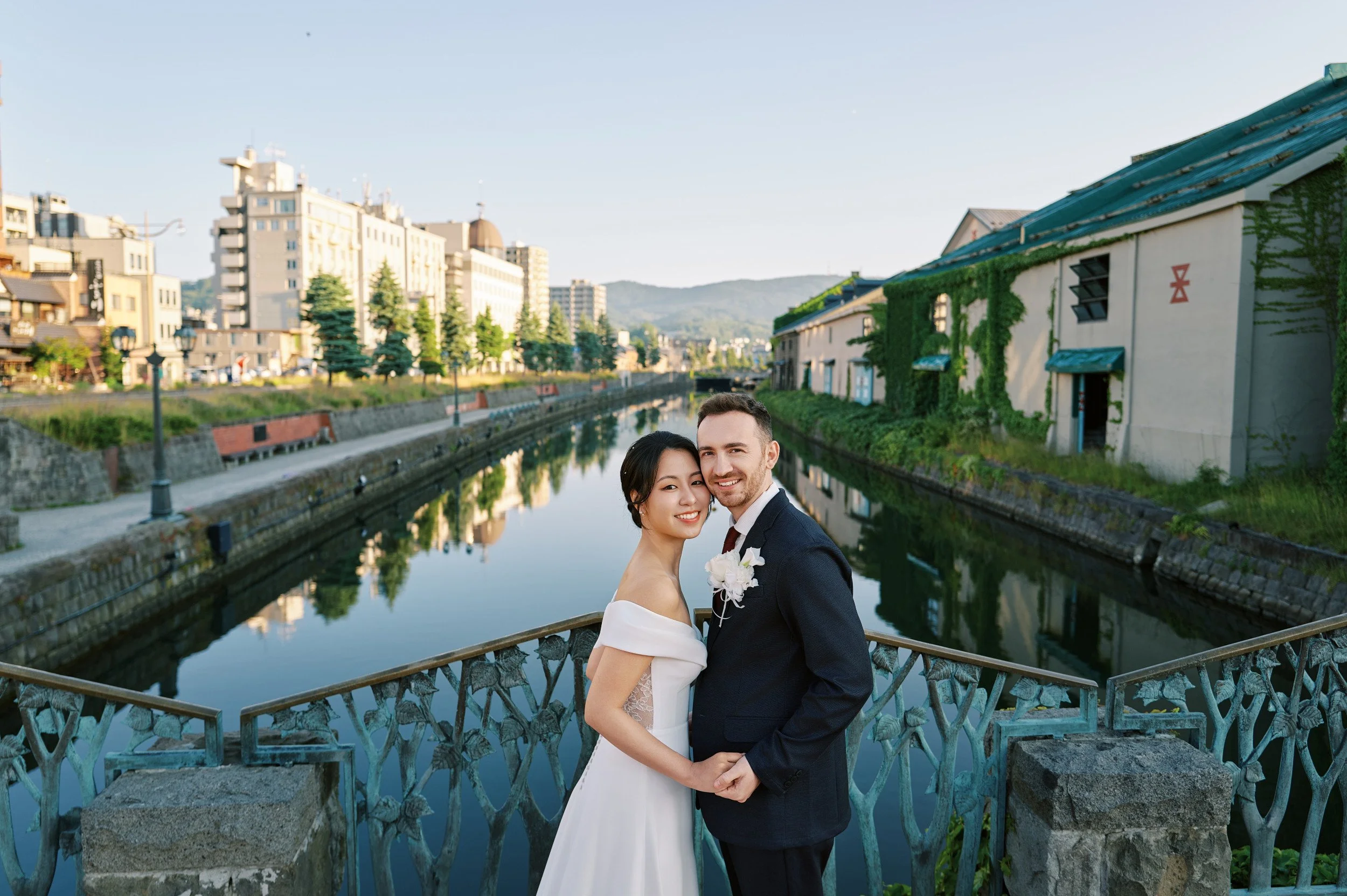 Bride and groom walking the cobblestone path beside the Otaru Canal in early morning light, Hokkaido