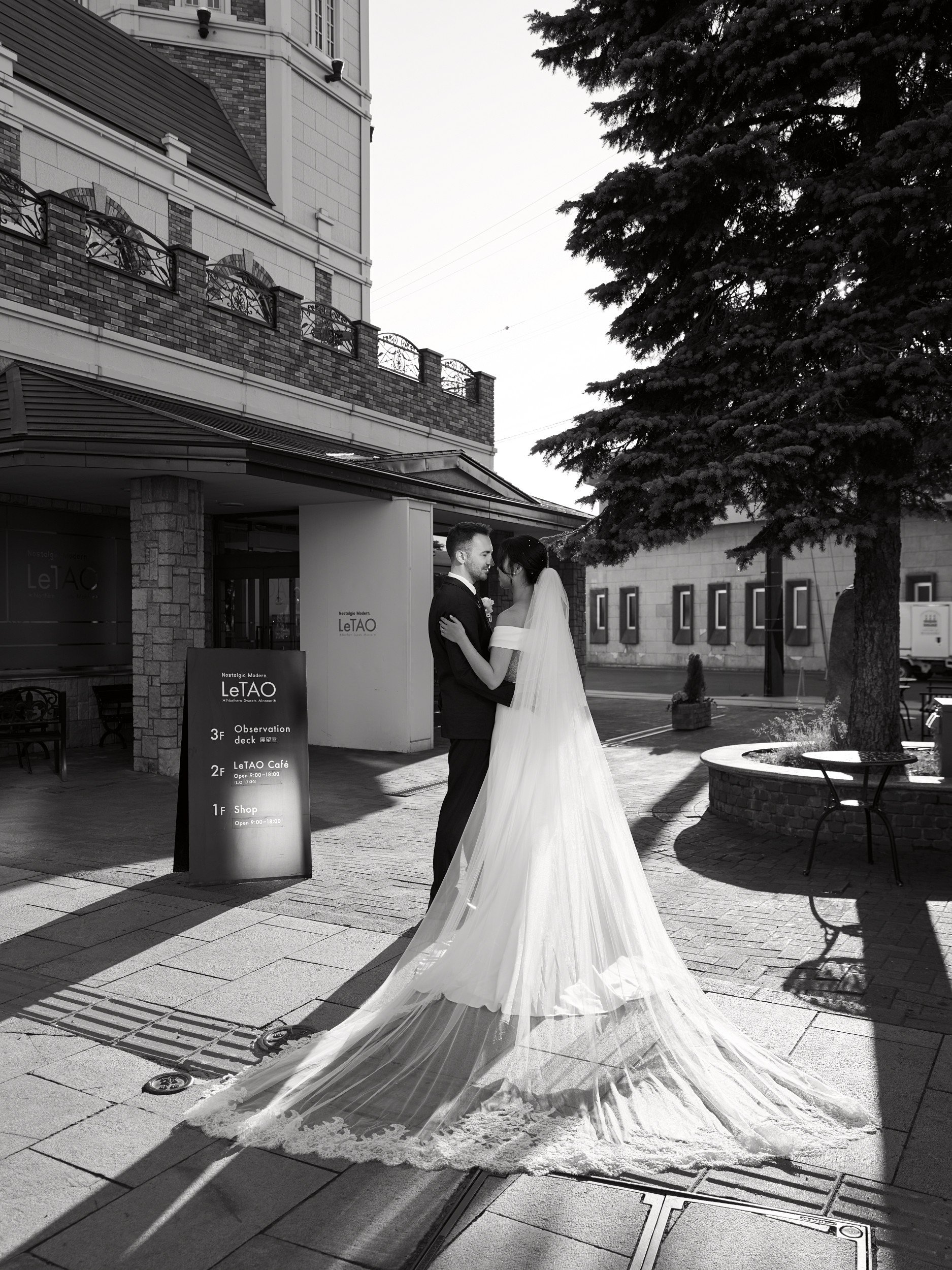 Bride laughing over the groom's shoulder on a quiet Otaru street in the morning