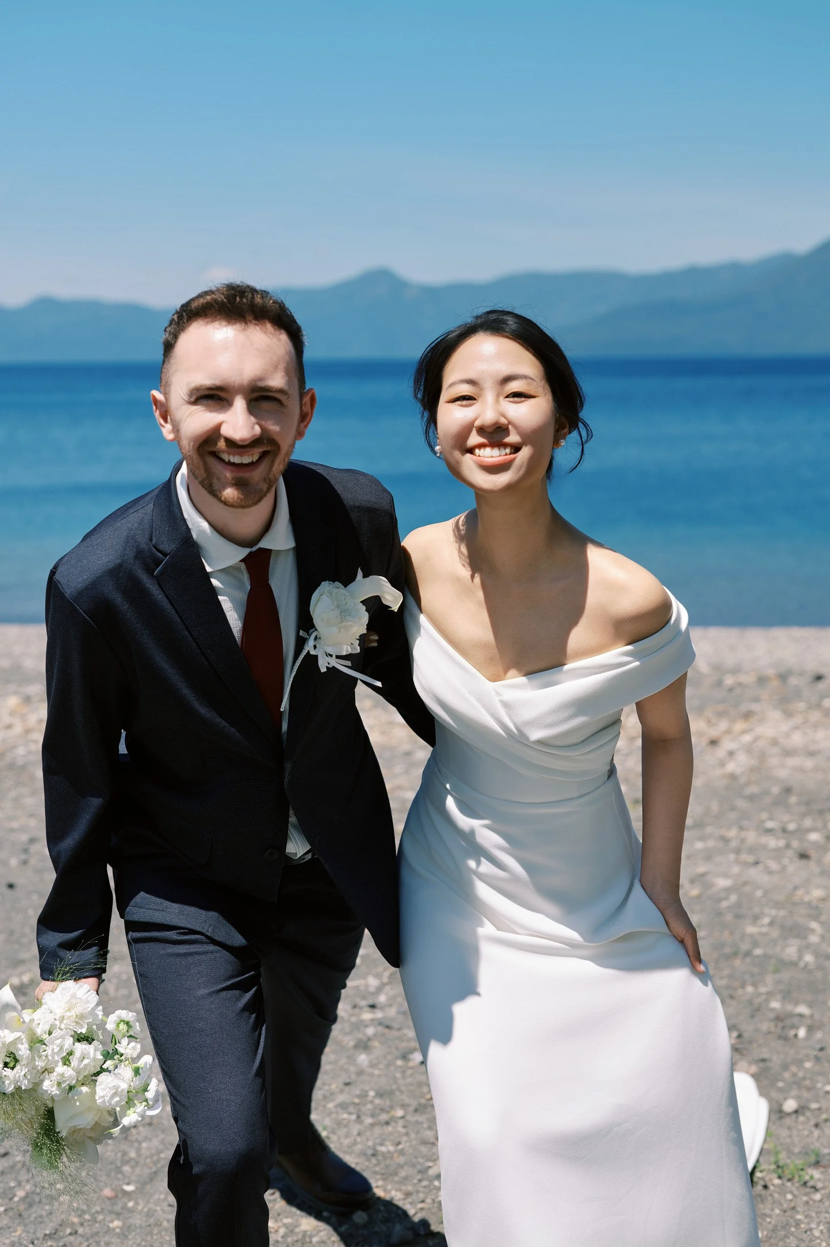 Close portrait of the couple laughing together beside Lake Shikotsu