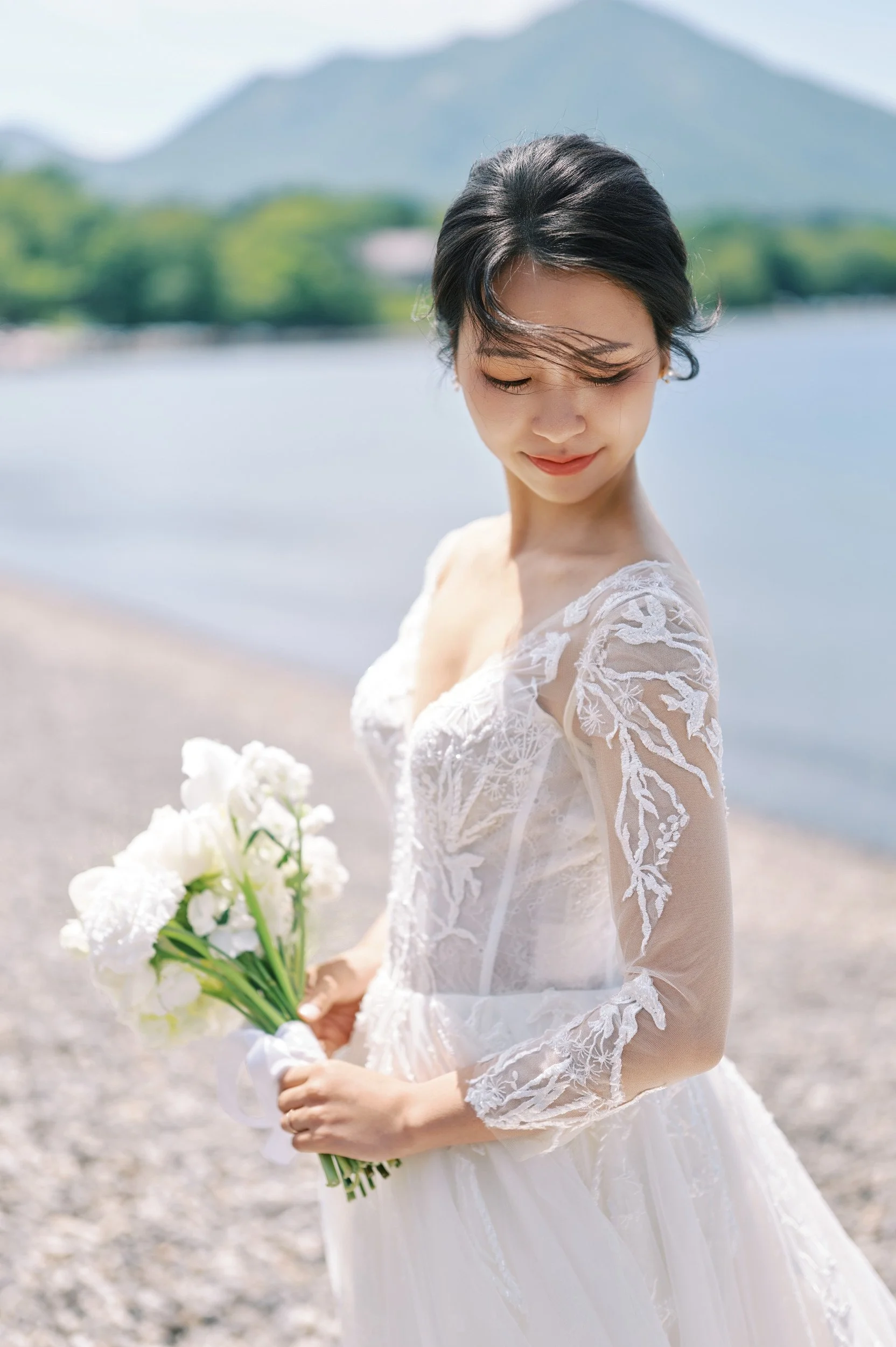 Bride's dress catching the breeze at the Lake Shikotsu shoreline