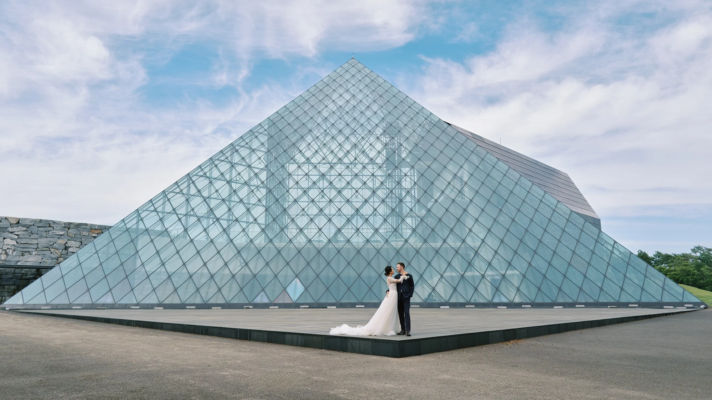 Quiet moment between the couple with the pyramid's glass panels catching the sky
