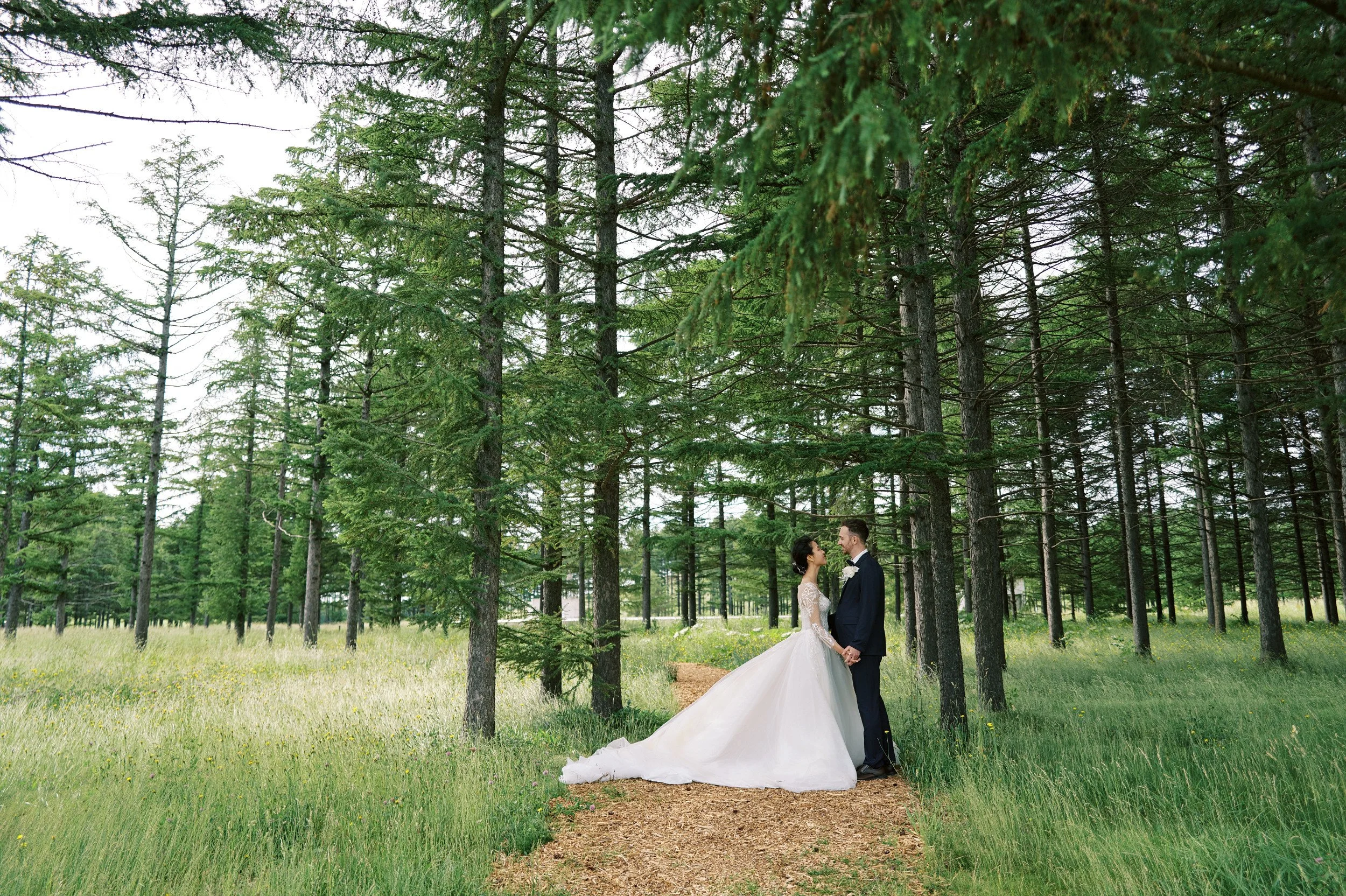 Bride and groom among the trees at Moerenuma Park in soft filtered light
