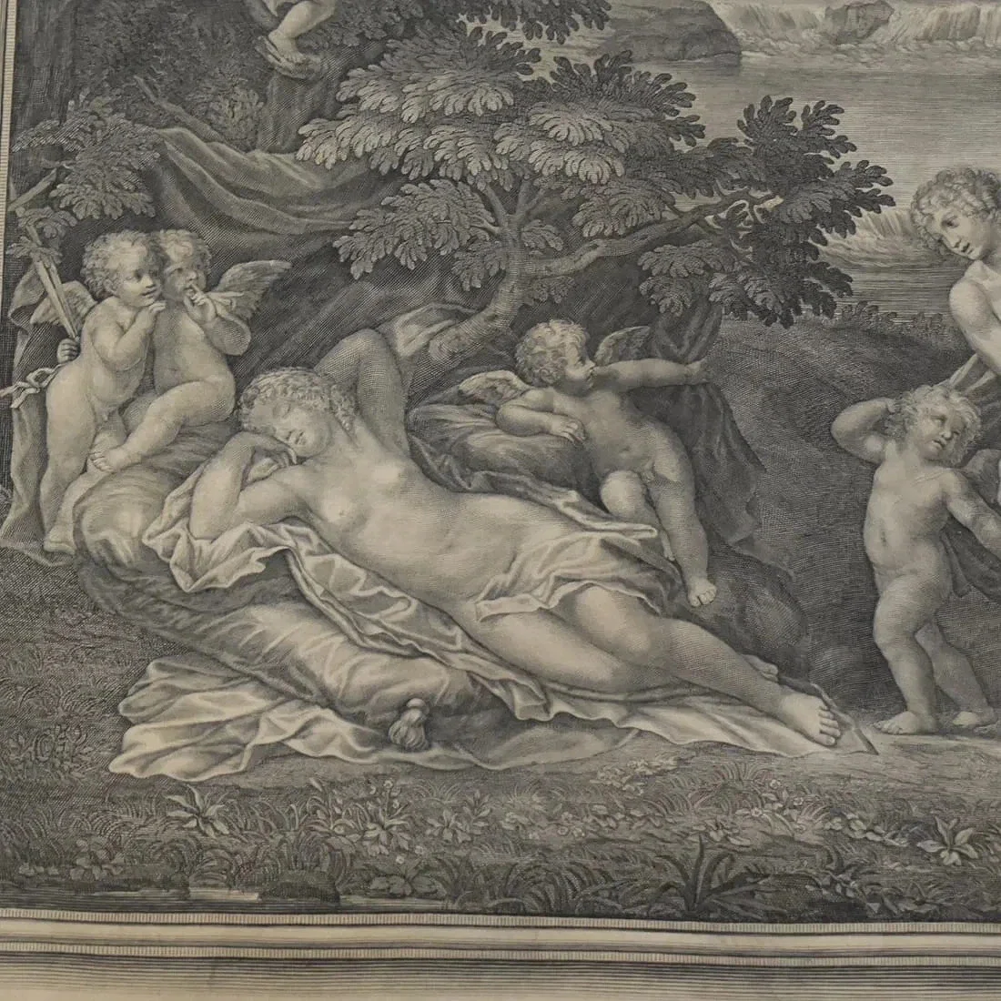 Black and white classical artwork depicting a reclining woman surrounded by cherubs and children in a natural outdoor setting with trees and landscape in the background.