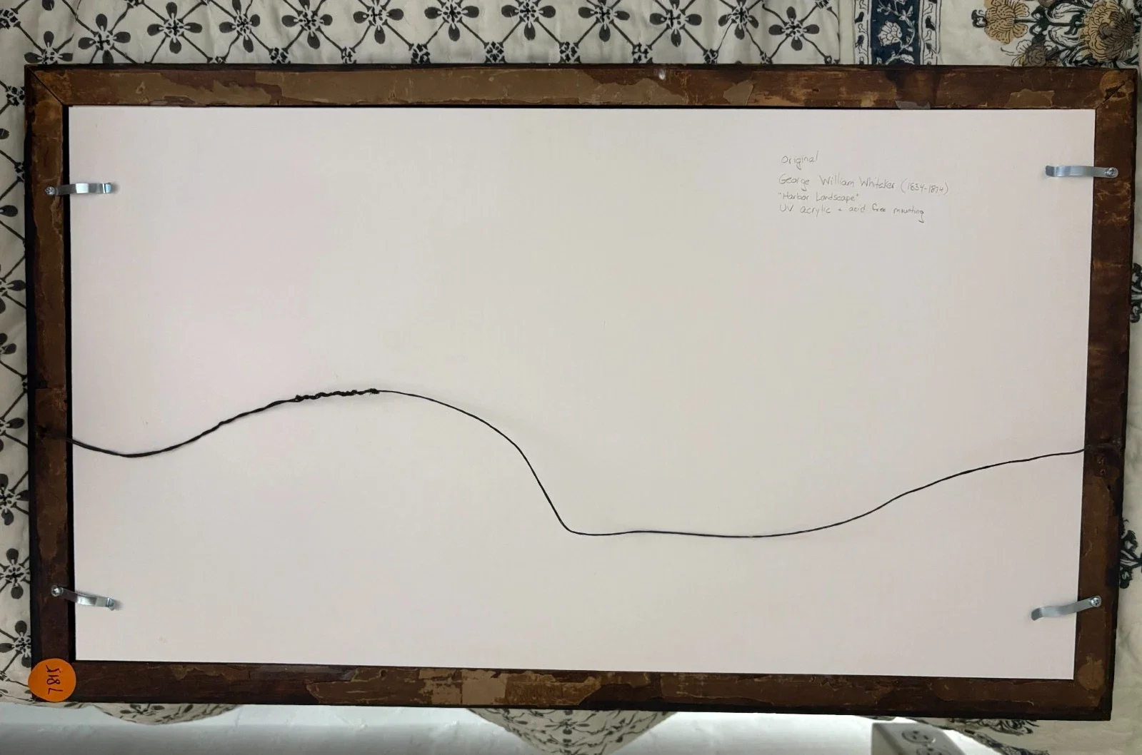 Back of a framed painting by George William Whistler titled 'Harbor Landscape' with a white canvas, a black wire for hanging, and a small orange sticker at the bottom left corner that has the year 1961 written on it.