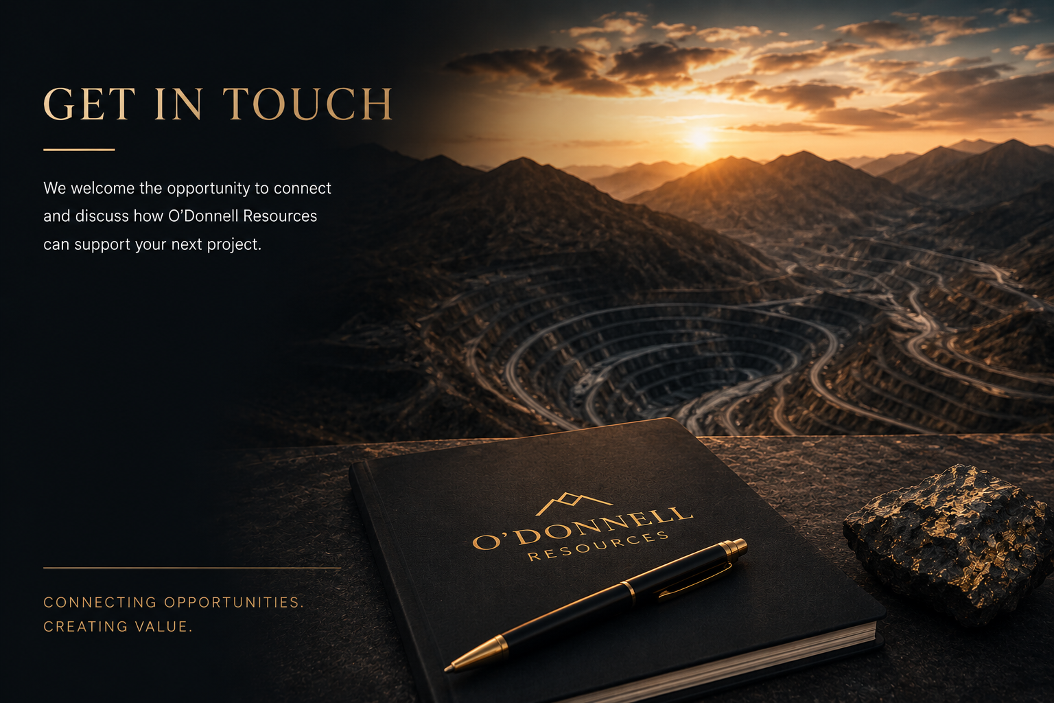 An office-style scene featuring a black notebook with O'Donnell Resources logo, a gold and black pen, and a textured rock, set against a backdrop of a mountainous landscape at sunset with a winding road in the valley.