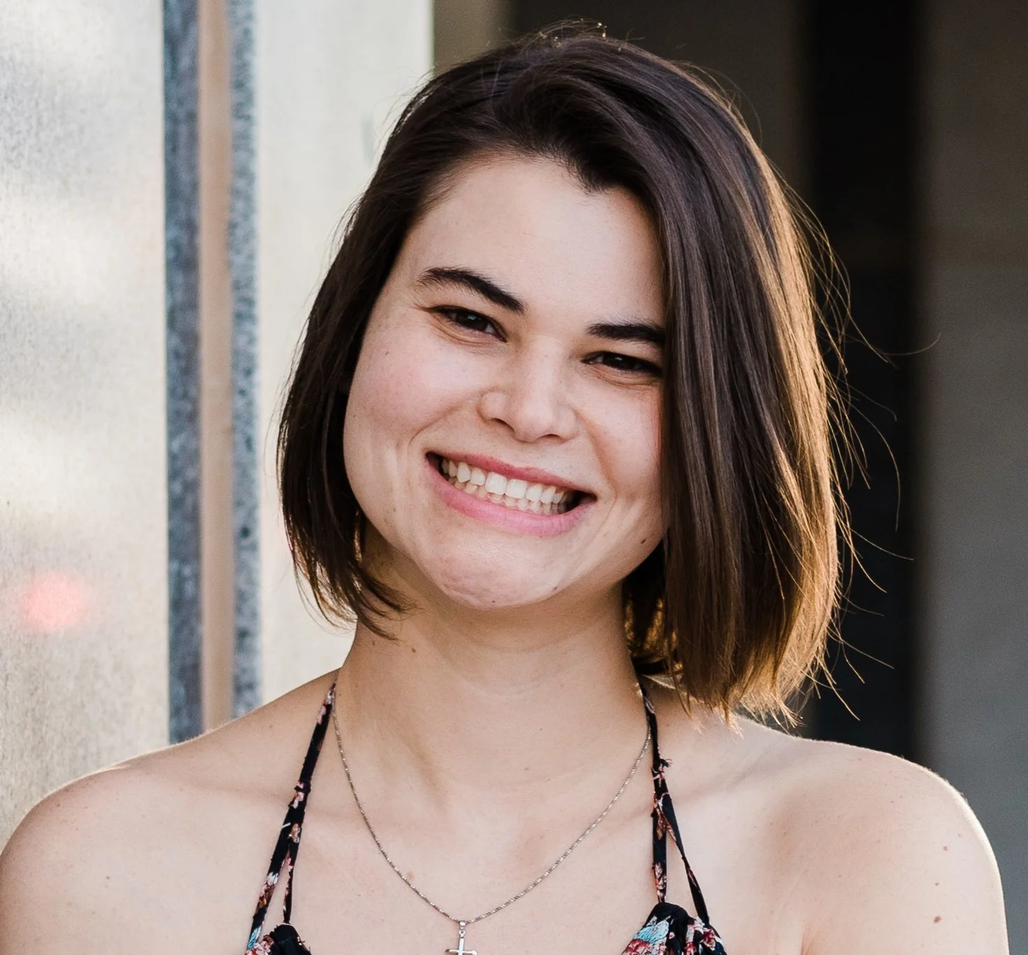 A young woman with short, dark brown hair smiling at the camera.