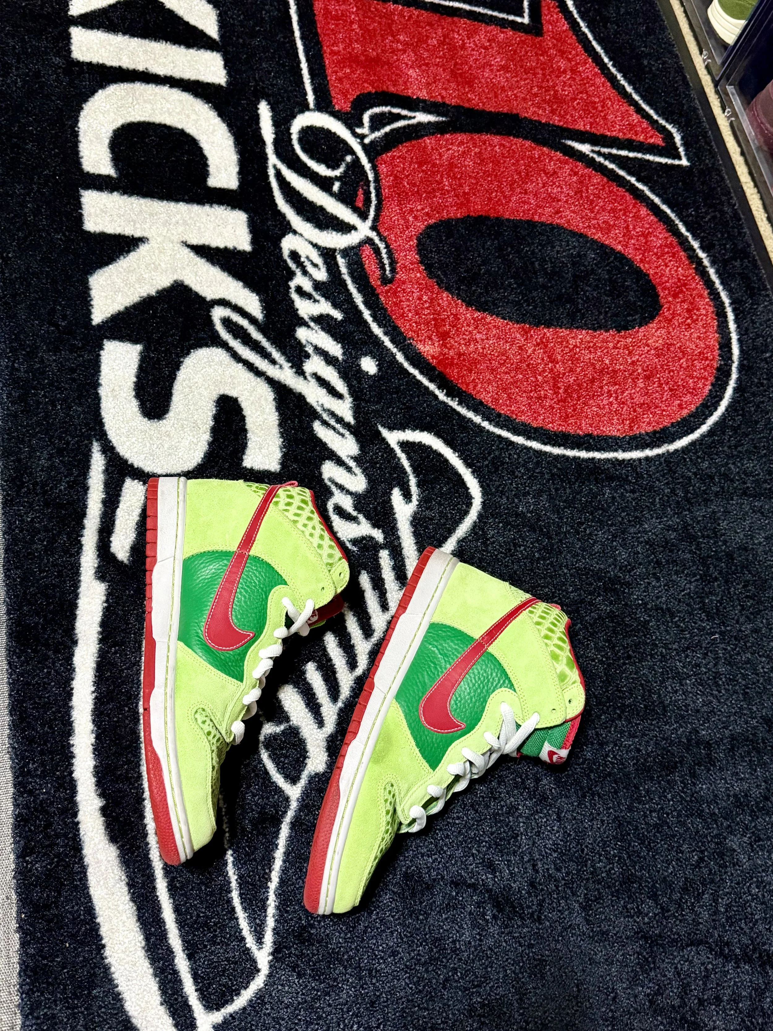 A pair of bright yellow sneakers with green and red accents on a black and red Omaha Raiders rug.