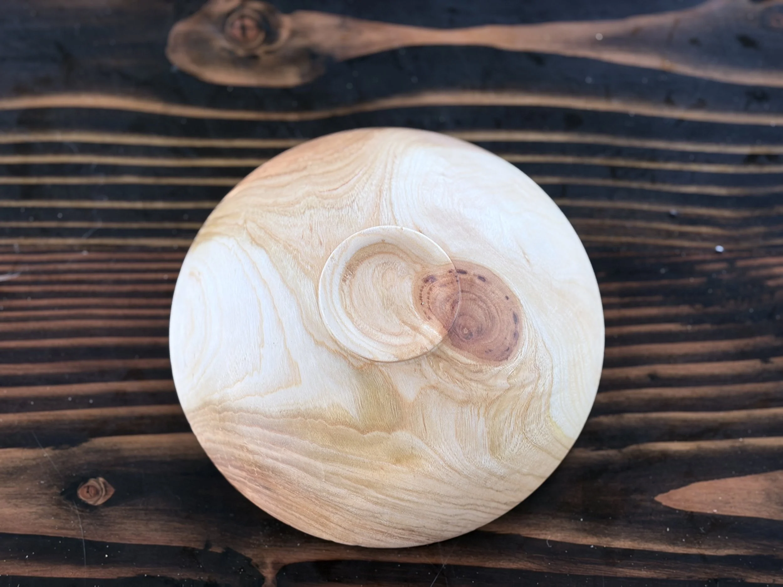 Close-up of a wooden spoon resting on a dark wooden surface.