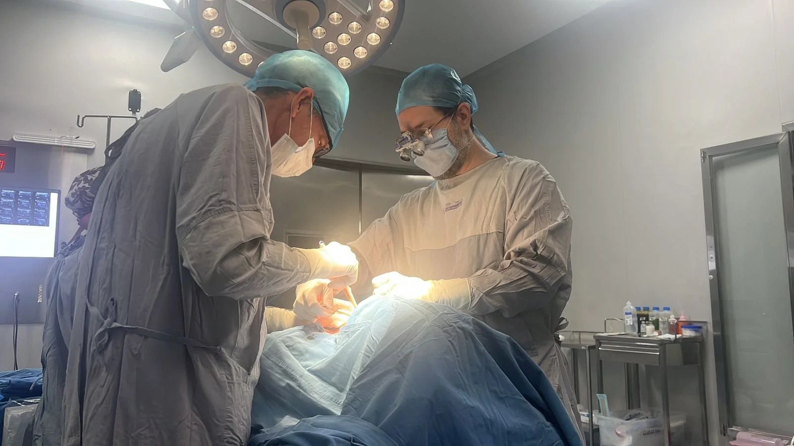 El Dr. Carlos Gustavo Rivera y otro cirujano en una operación de tiroides en un quirófano con iluminación adecuada y equipo médico.