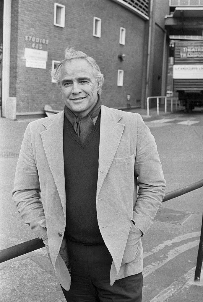 Actor and movie star Marlon Brando is pictured outside of a building smiling in the 1980s.