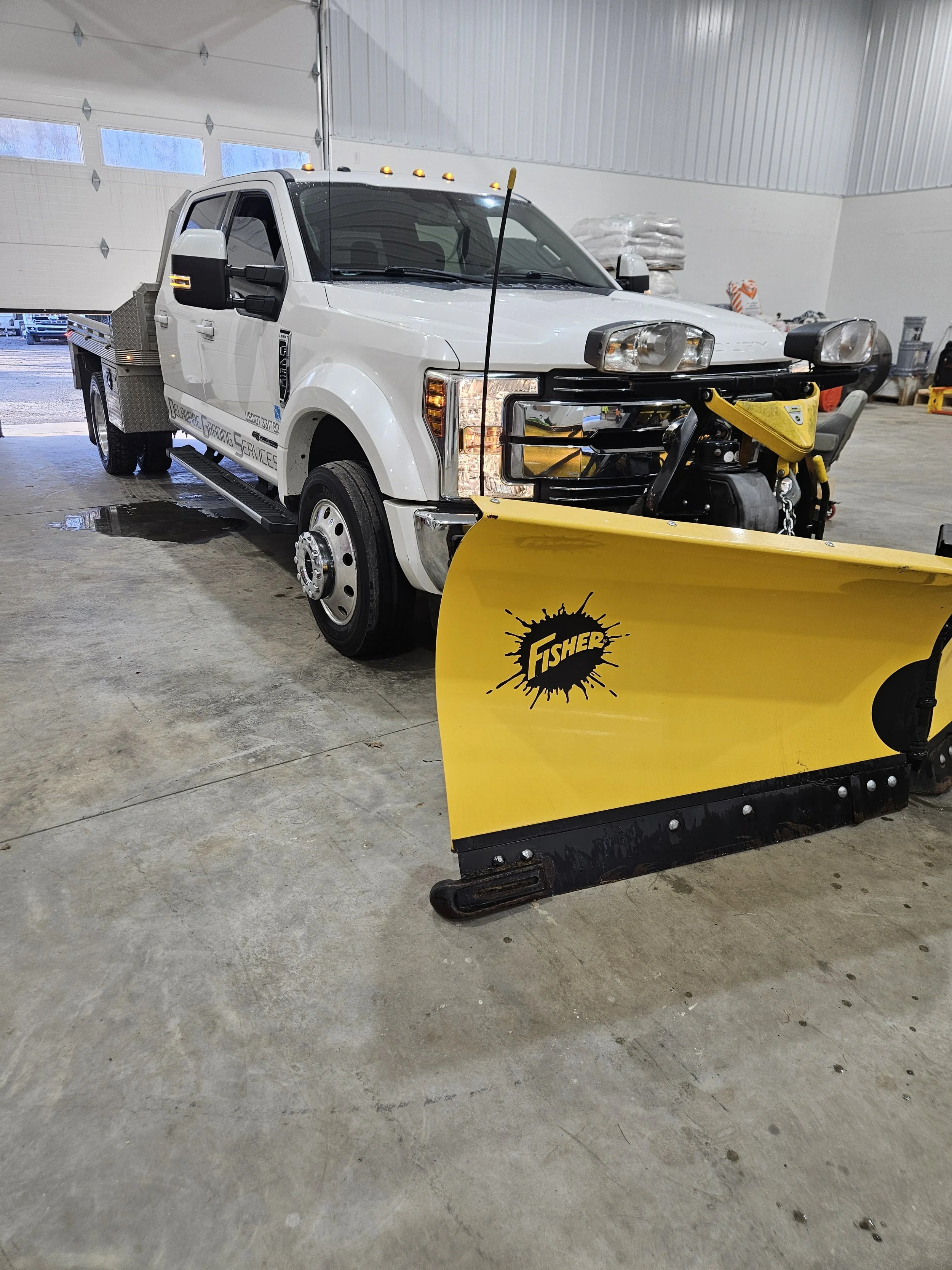 A white utility truck with a snow plow attached to the front, showcasing Delaware Grading services Snow removal