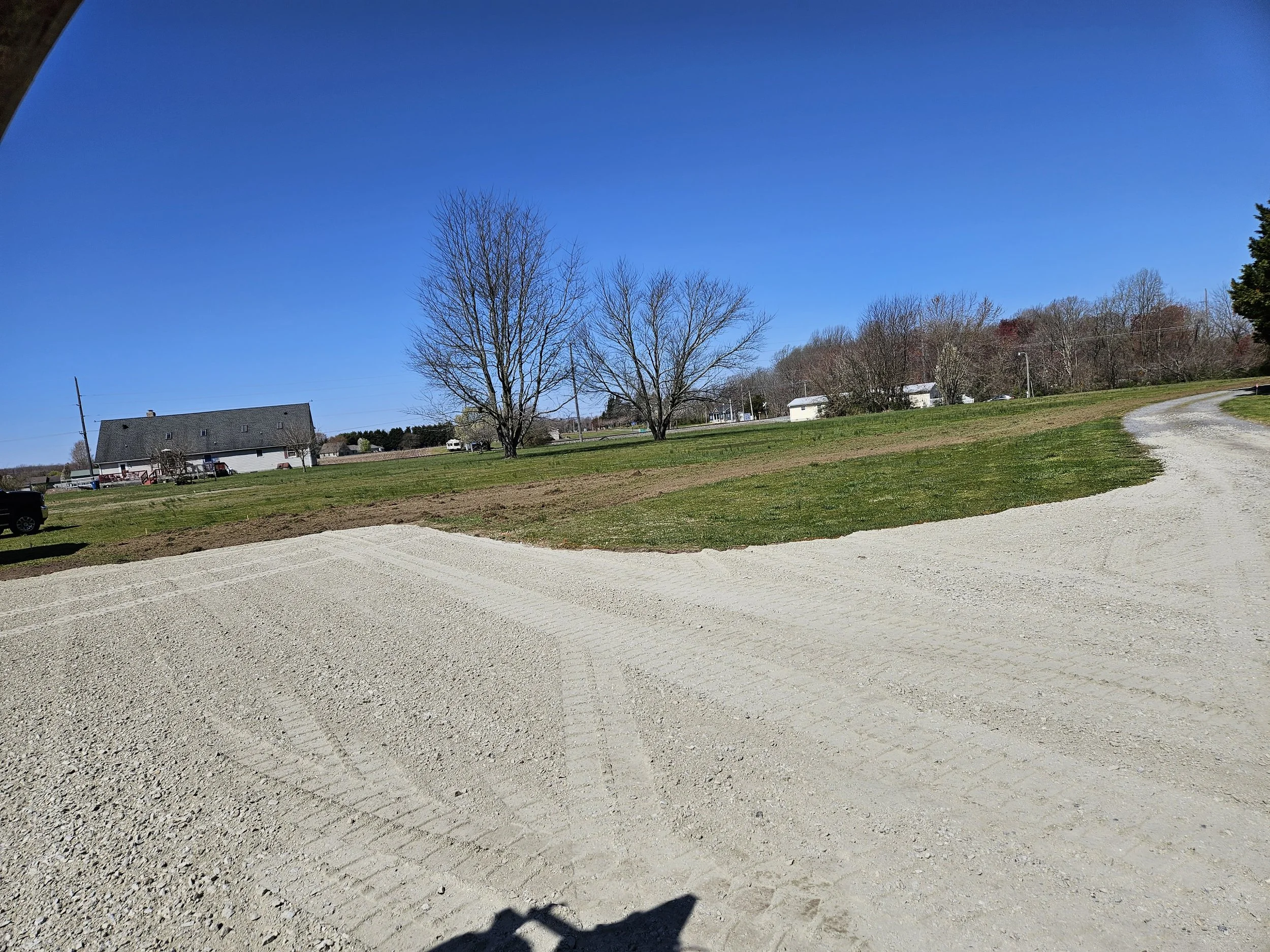 A rural landscape with a gravel driveway that has been installed by Delaware Grading Services
