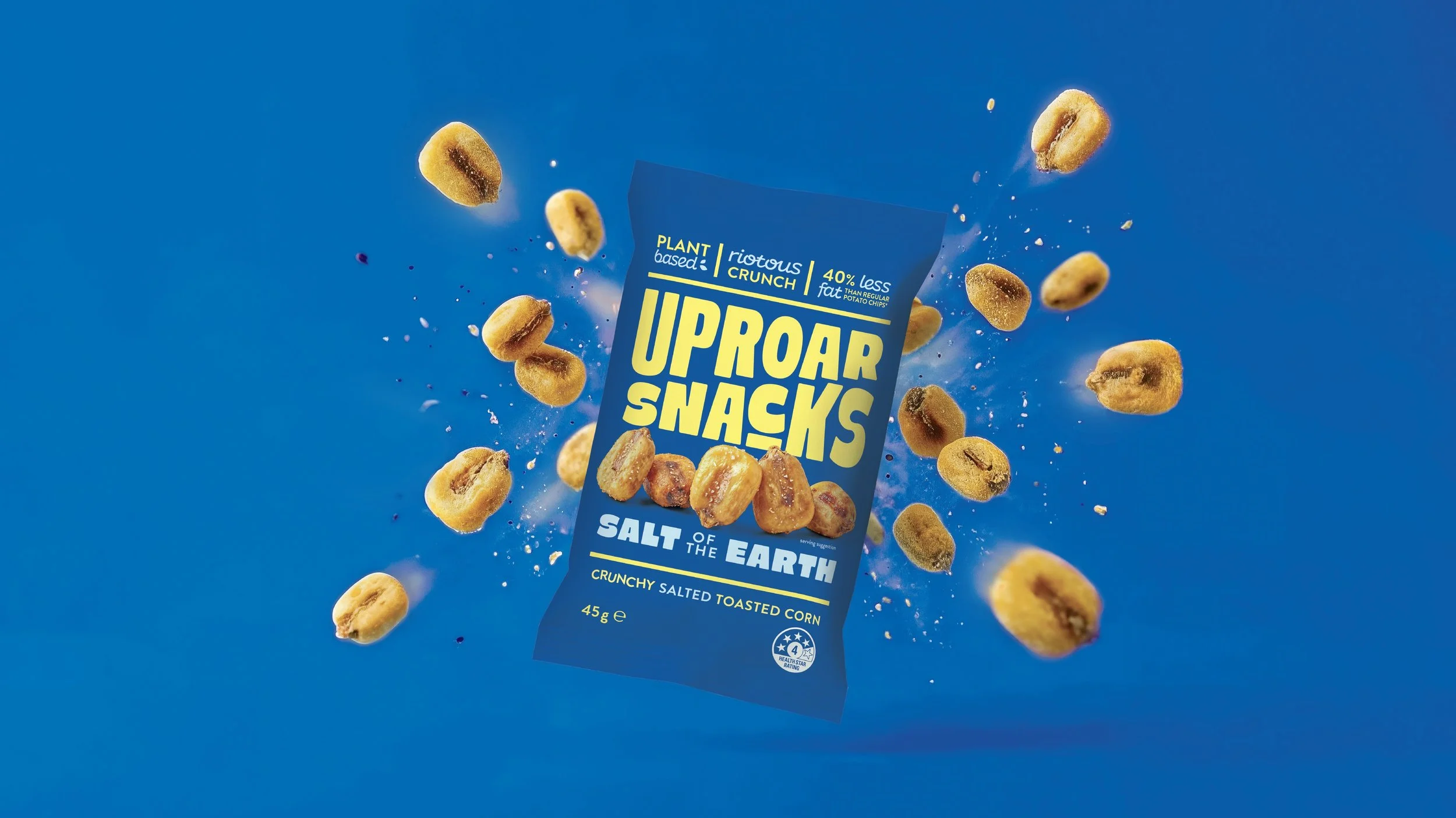 Bag of plant-based Uproar Snacks Salt of the Earth crunchy salted toasted corn, with corn kernels flying around against a blue background.