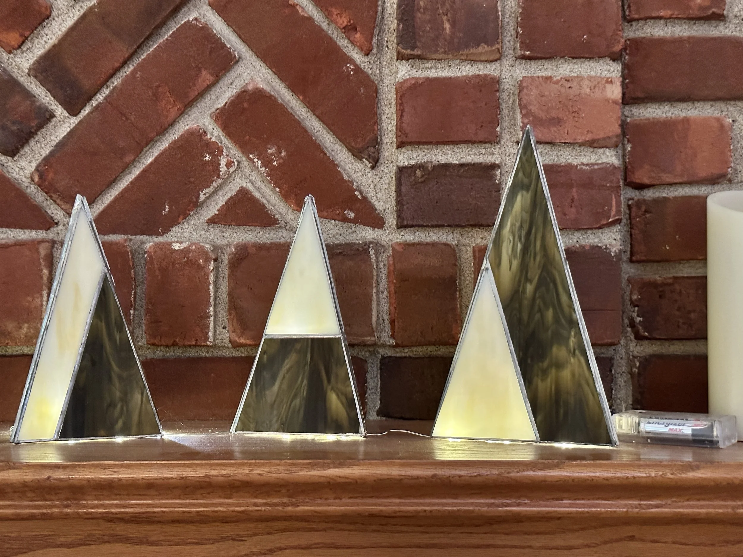 Decorative fireplace mantel with a row of triangle-shaped glass ornaments with iridescent surfaces.