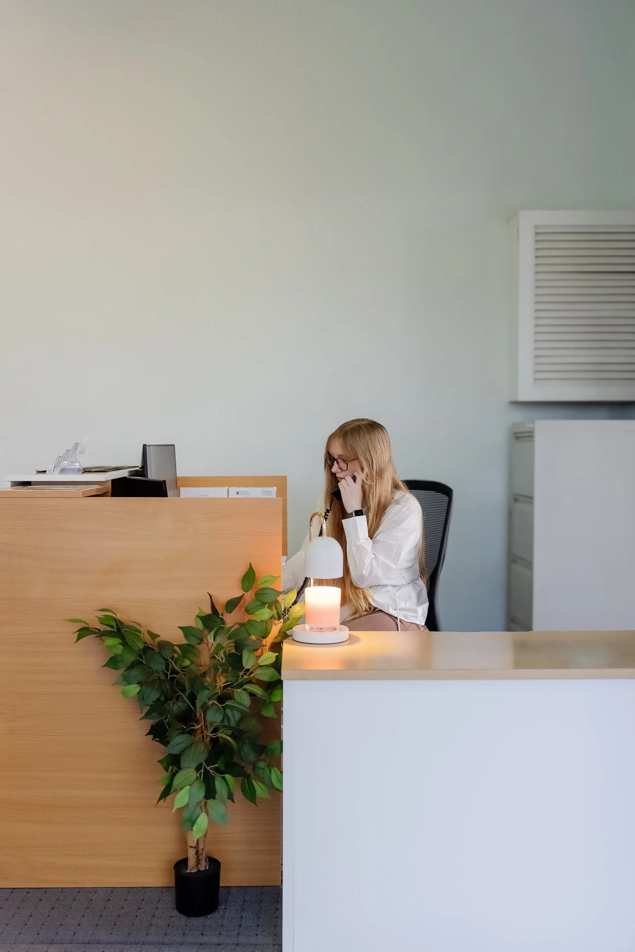 Samara Ingram Receptionist/Legal Assistant sitting at a reception desk, talking on the phone.