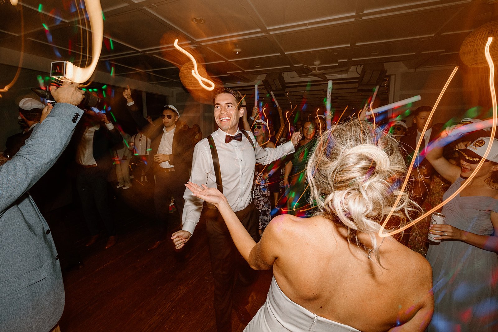People dancing and celebrating at a lively party with colorful lights and a festive atmosphere.
