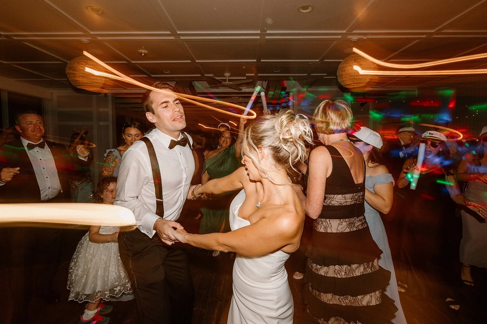 People dancing at a lively party or celebration, with colorful lights and a festive atmosphere.