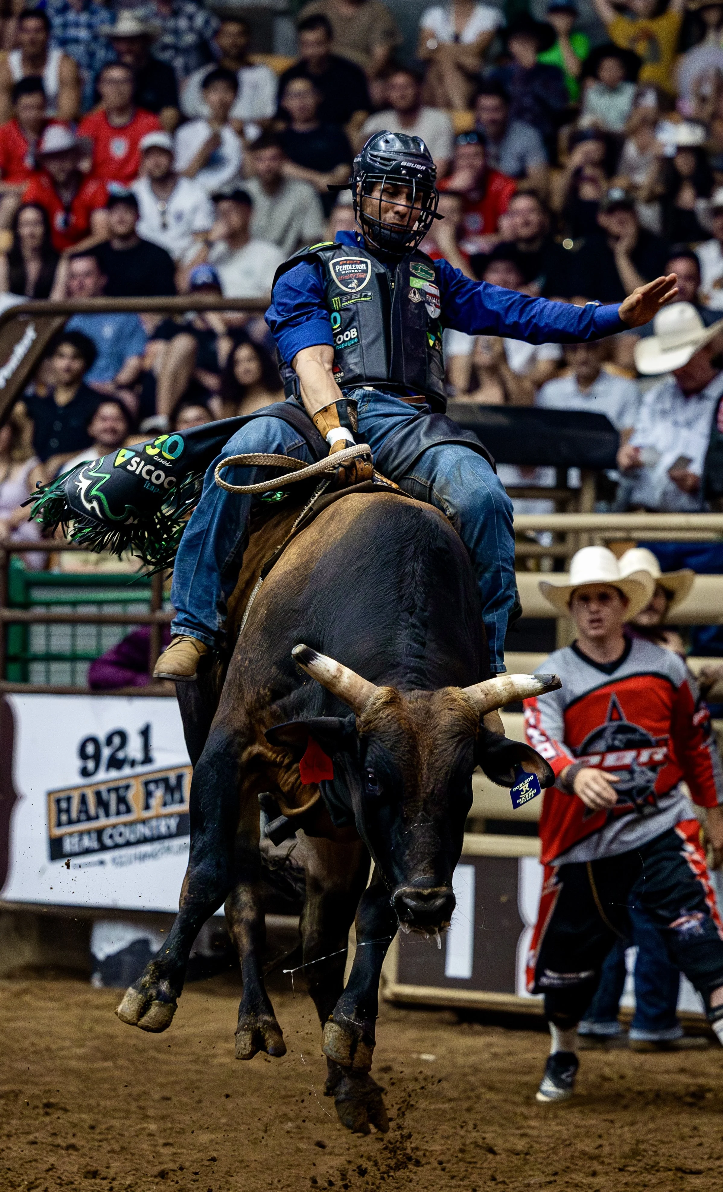 A cowboy riding a bull in a rodeo arena.