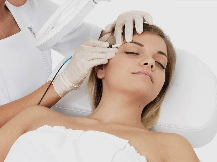 Woman receiving a cosmetic or medical treatment on her face from a professional wearing gloves.