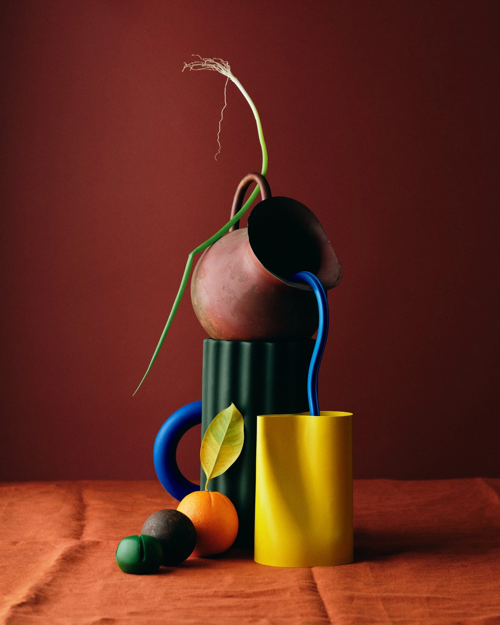 Colorful abstract still life composition with vases, a lemon, and fruits on a wooden surface.