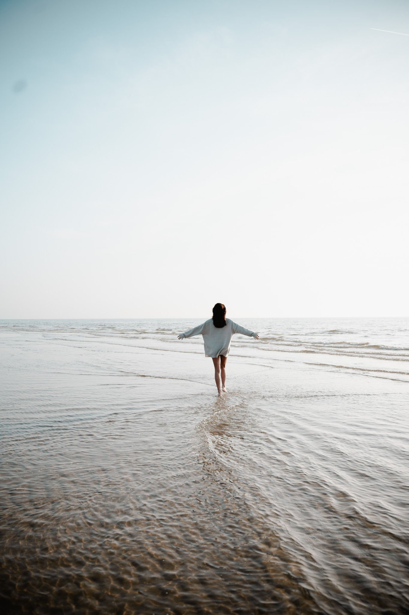 Vrouw staat vrij met armen gespreid aan de zee – identiteitstransformatie en doorbraakbegeleiding bij Praktijk Terra Nova