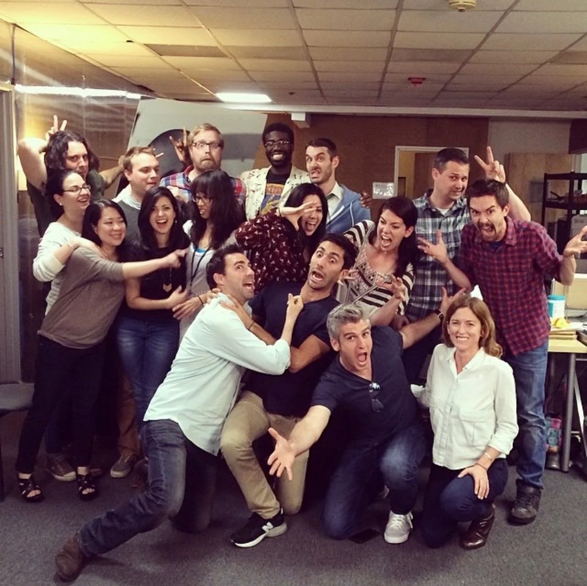 A group of people posing together in a room, appearing to be having fun with various playful and exaggerated expressions.
