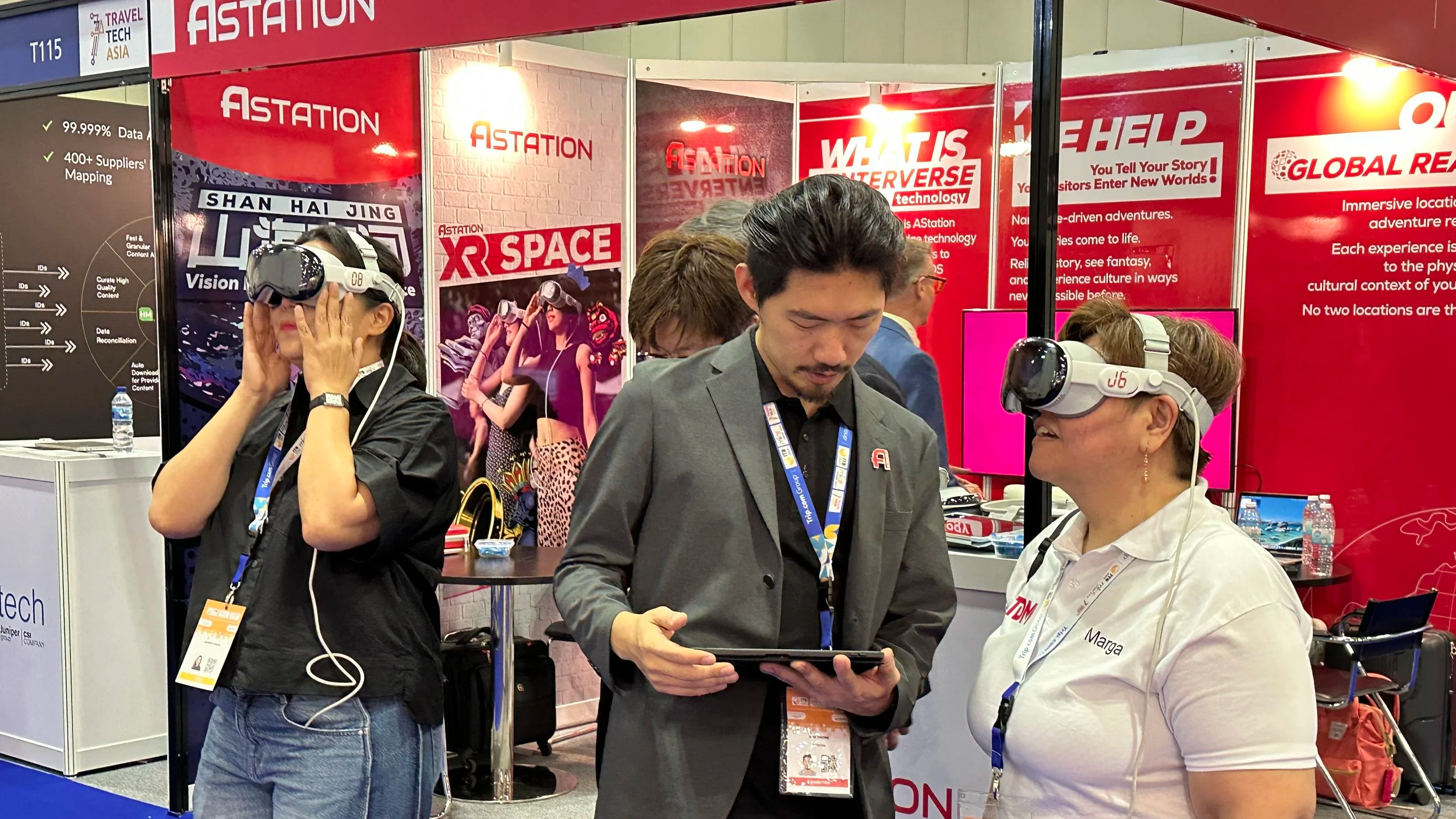 Journalists at a booth with virtual reality headsets and promotional banners in the background to launch AStation's Enterverse™ technology in Singapore at ITB Asia 2025.