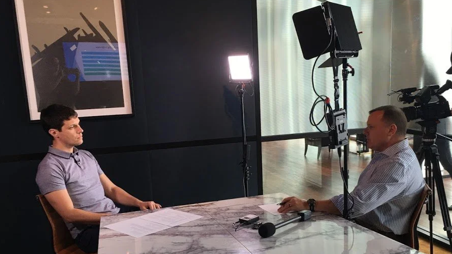 Two men engaged in a media training session organised by Pinpoint PR,  with professional lighting and camera equipment.
