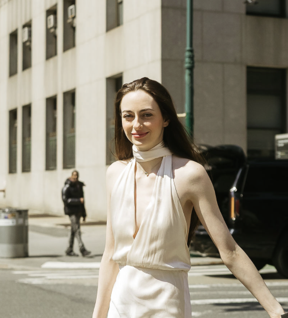 A stylish bride smiling in her wedding attire on a classic New York City street after her elopement ceremony.