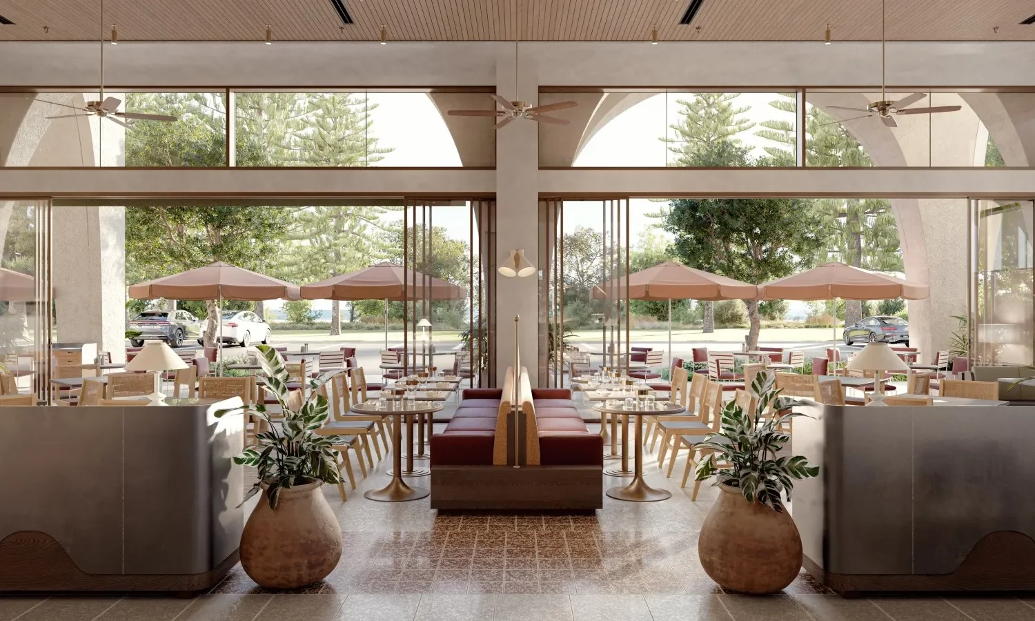 Interior of a restaurant with large windows, tables set with glassware, and outdoor patio umbrellas visible through the windows.