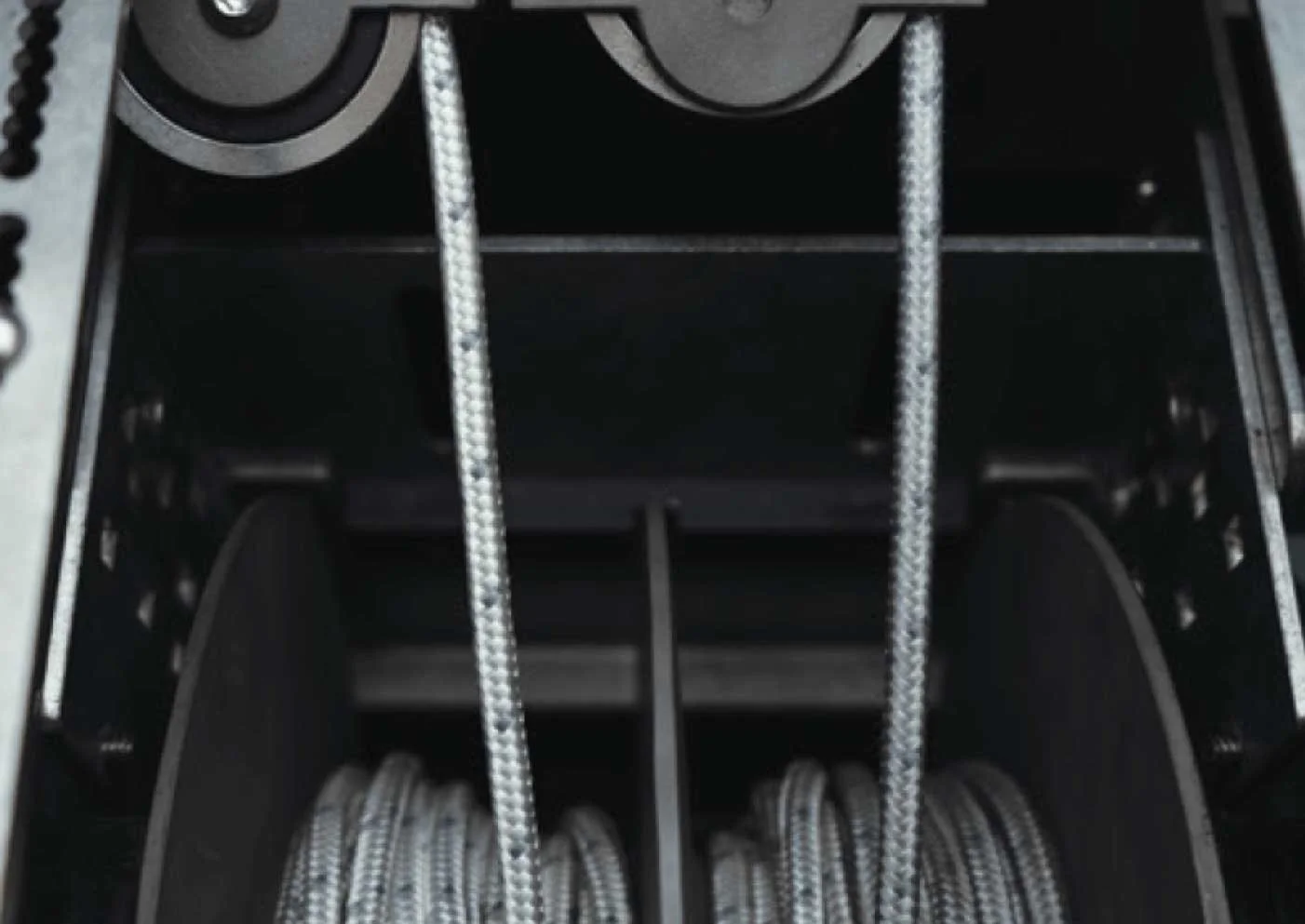 A black nylon fishing tackle box with two compartments holding coiled braided fishing lines and a pair of silver braided fishing lines draped over the sides.