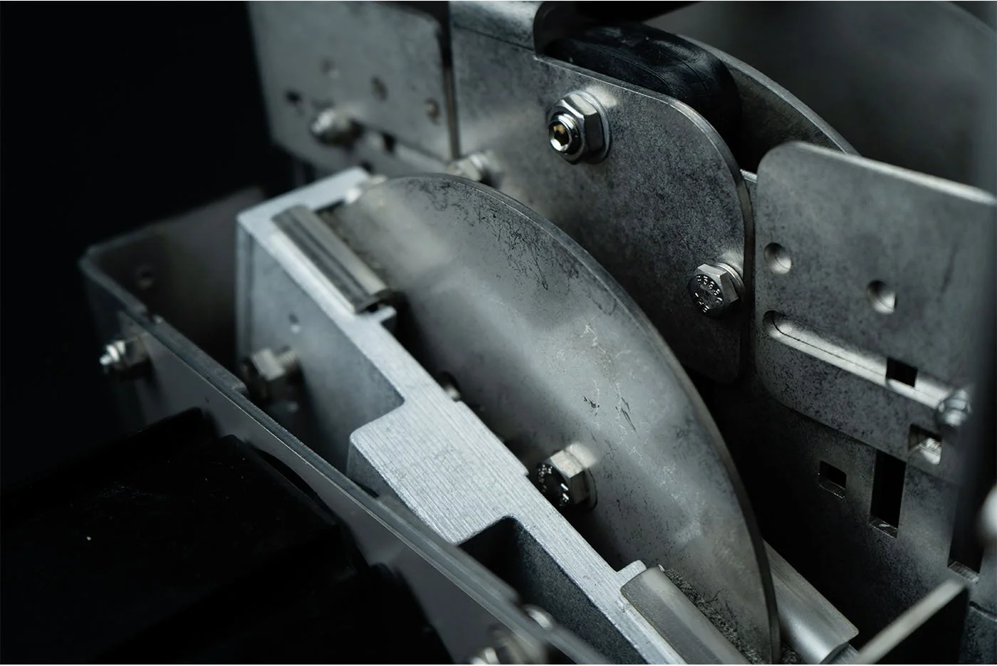 Close-up of an industrial machine with metallic components, bolts, and a roller