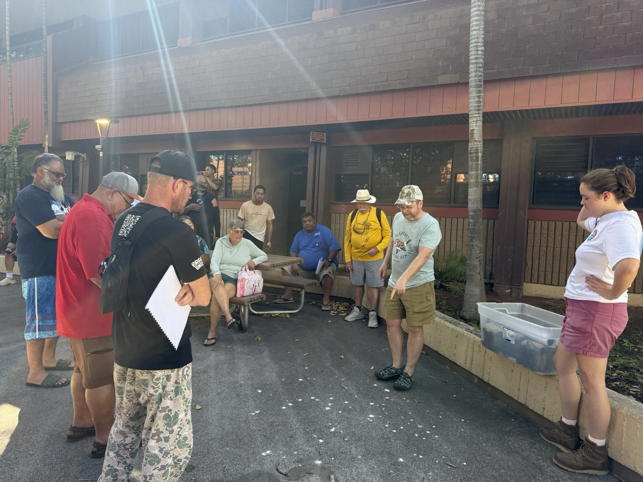 A workshop instructor points out manu o Kū guano on the ground at Kapi'olani Community College Campus, indicating an active nesting site overhead, during the afternoon workshop session.