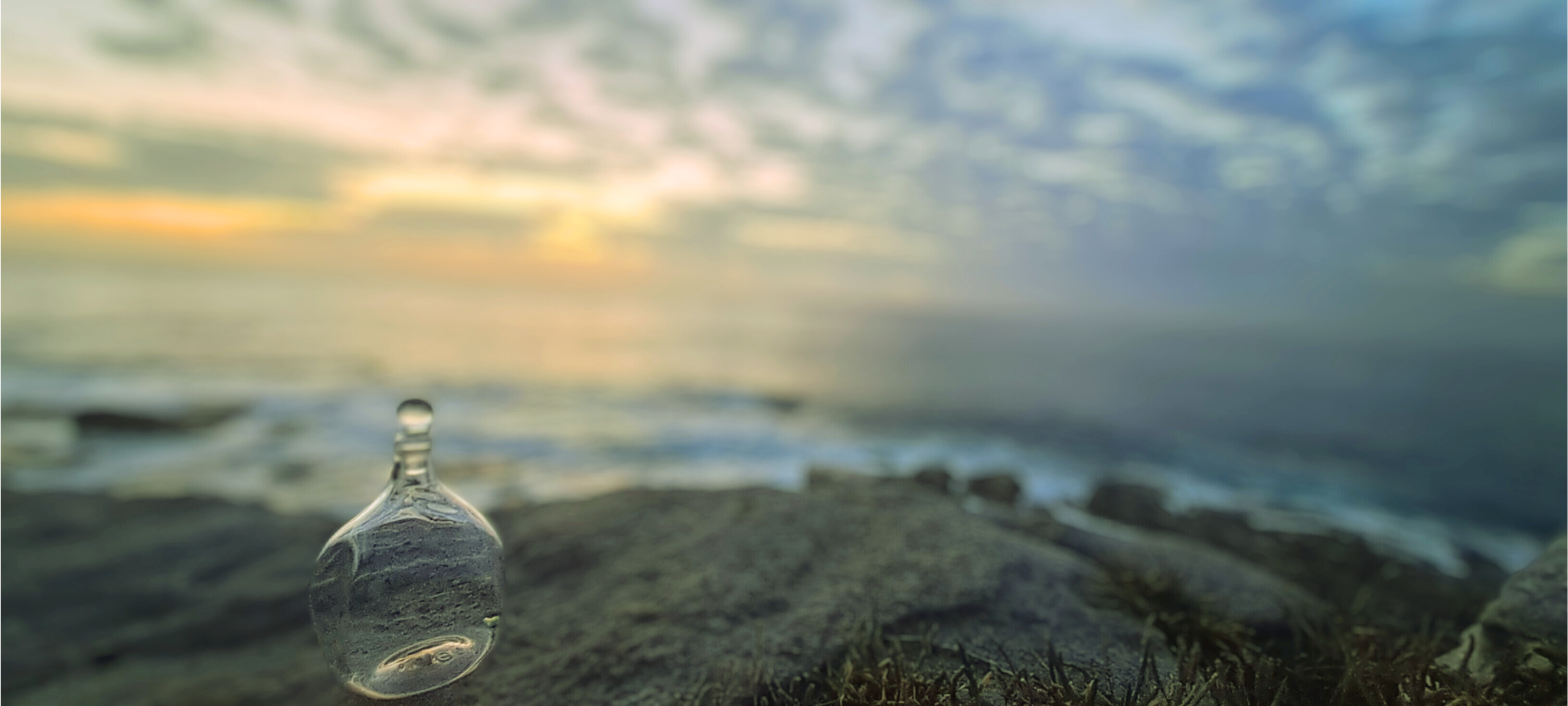 Handblown bottle on rocks overlooking sea
