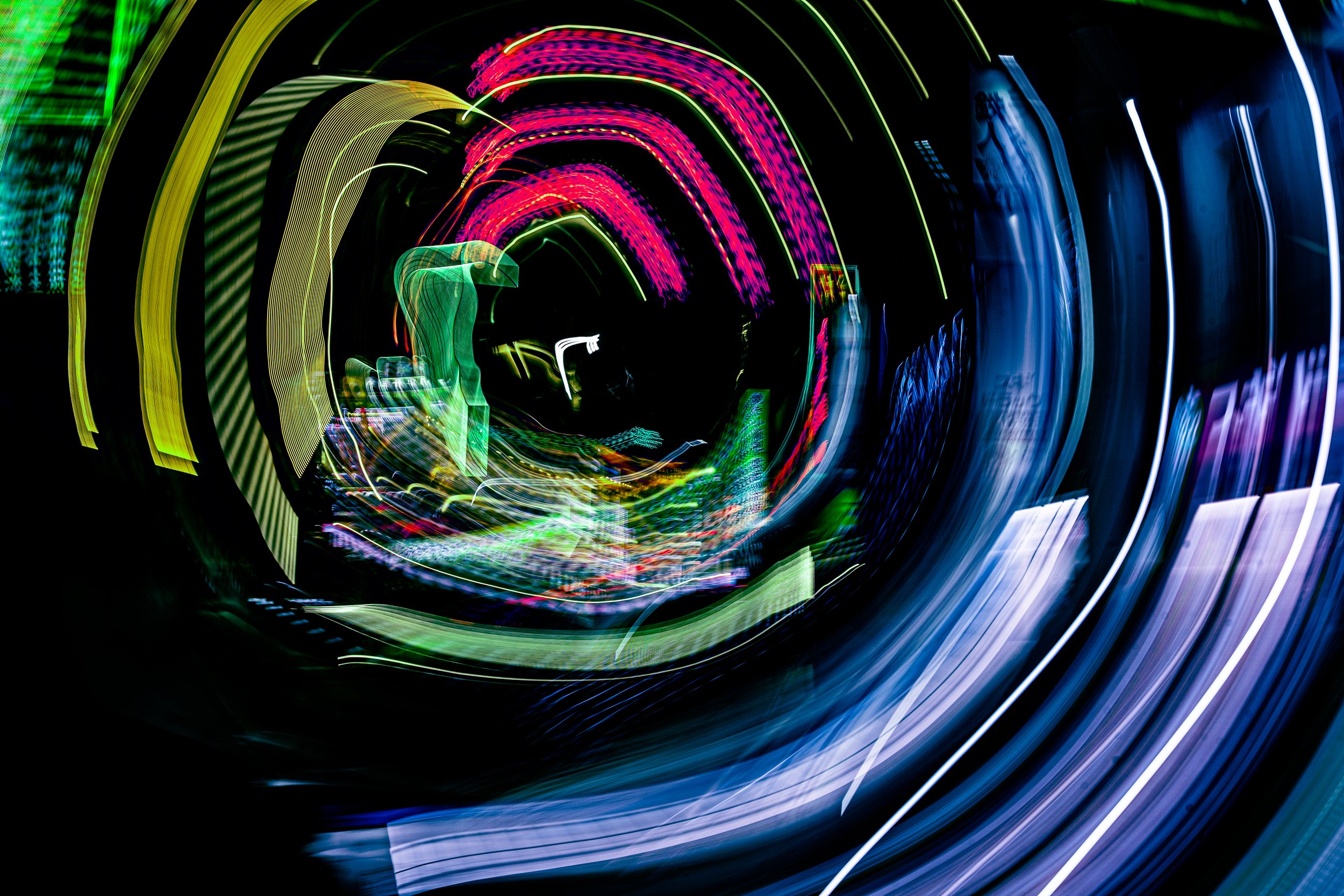 Colorful light trails forming an tunnel with purple, pink, green, blue, and yellow streaks against a black background.